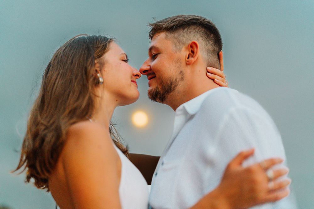 A couple shares an intimate moment against a soft blue background.