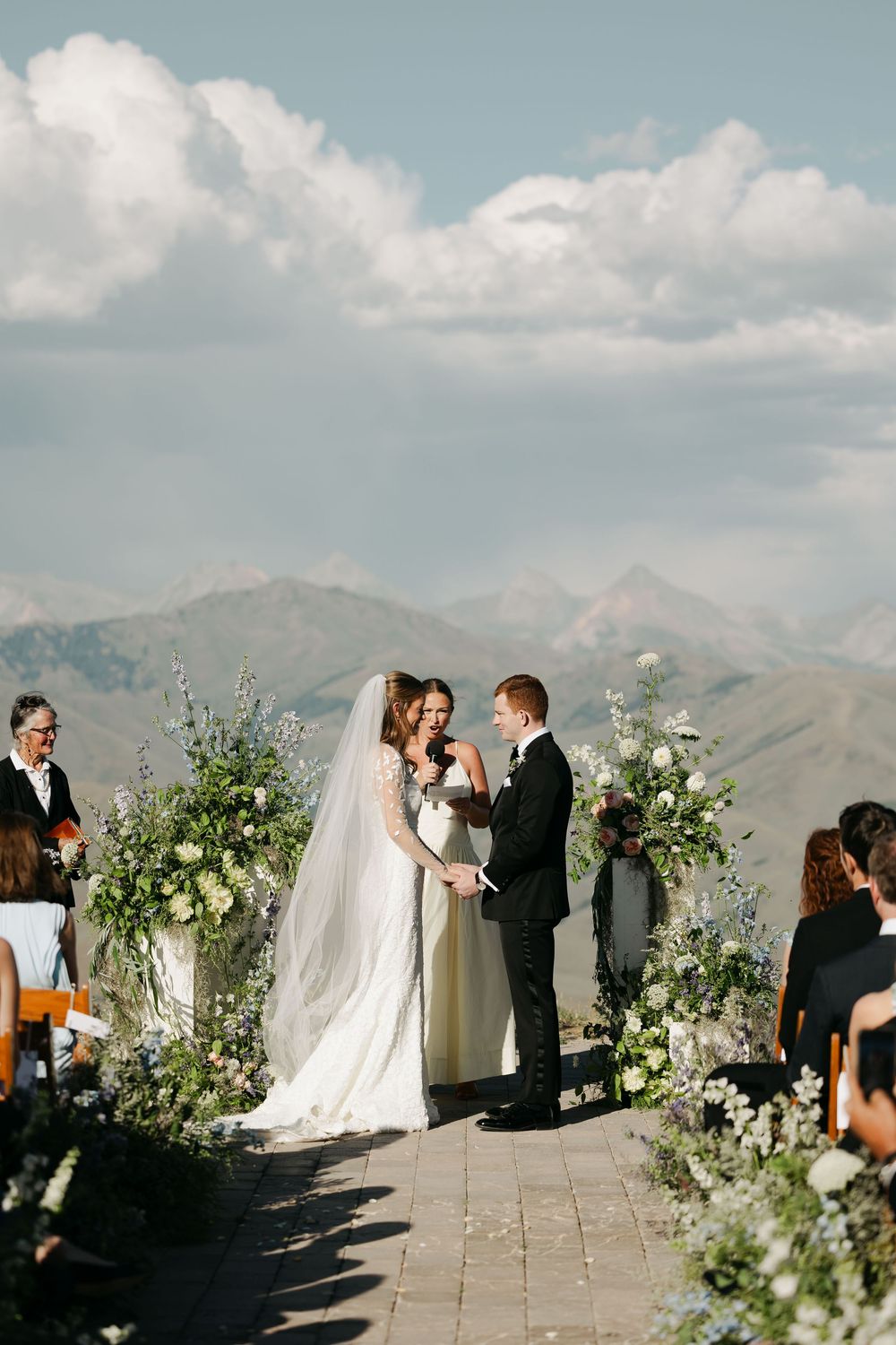 Wedding ceremony site decorated with white floral arrangements on a mountain overlook.