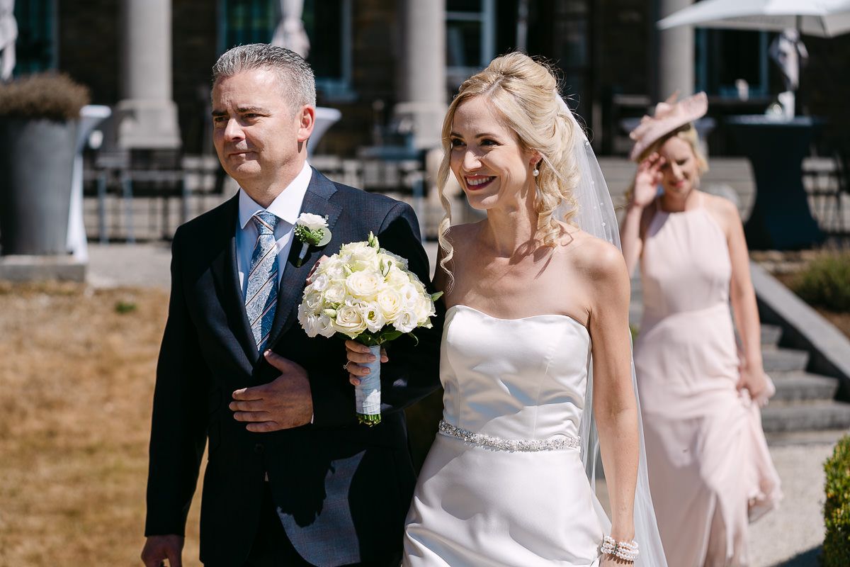 Bride and father walking into garden ceremony at Manoir de Lébioles
