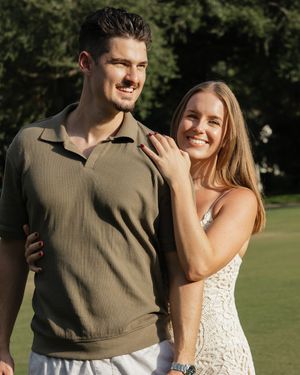 Couple shares intimate moments and laughter in outdoor garden photoshoot.