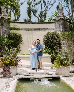 Couple sharing tender moments by a garden pond surrounded by tropical plants.