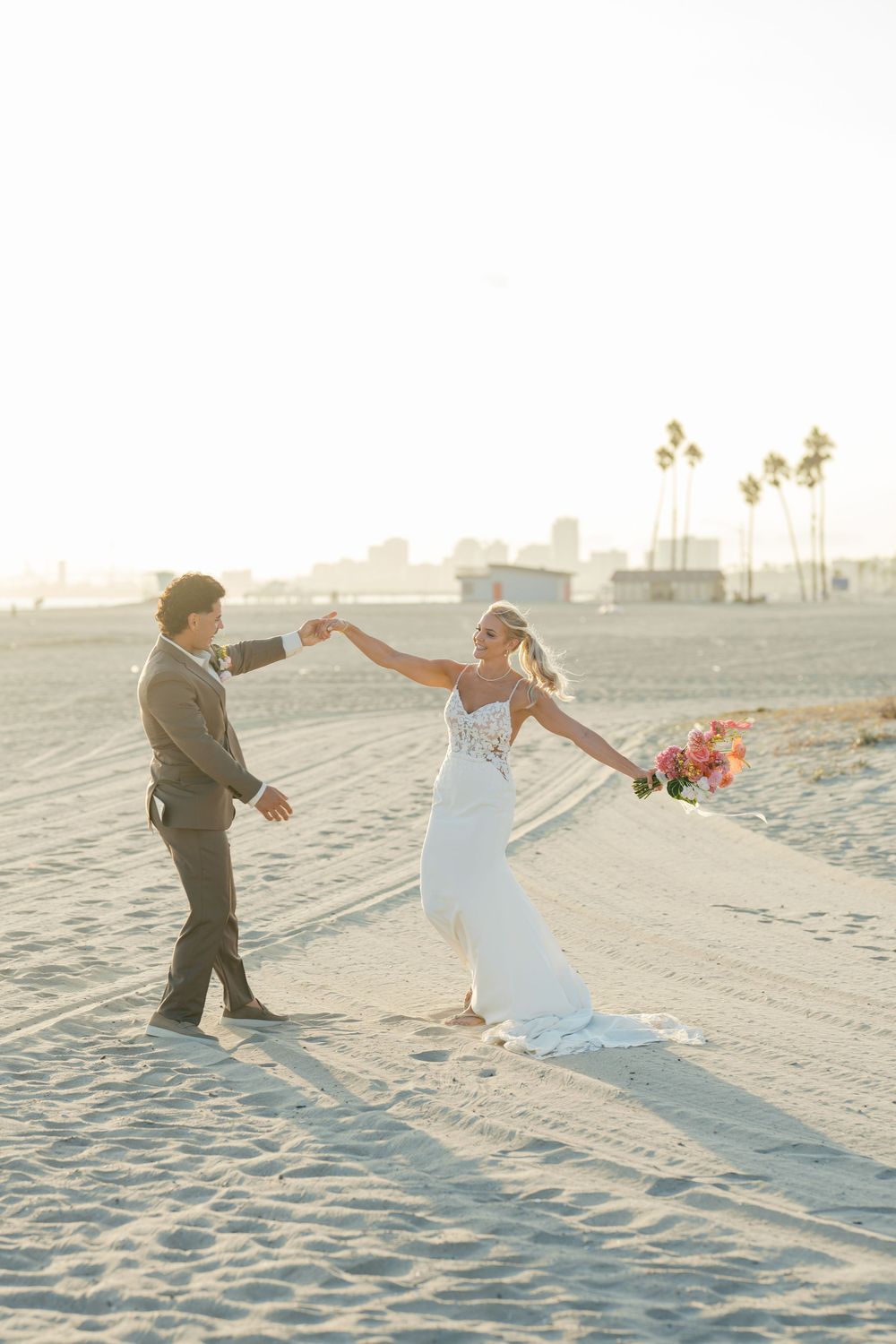 A romantic beach wedding photoshoot with dancing on the sand during sunset.