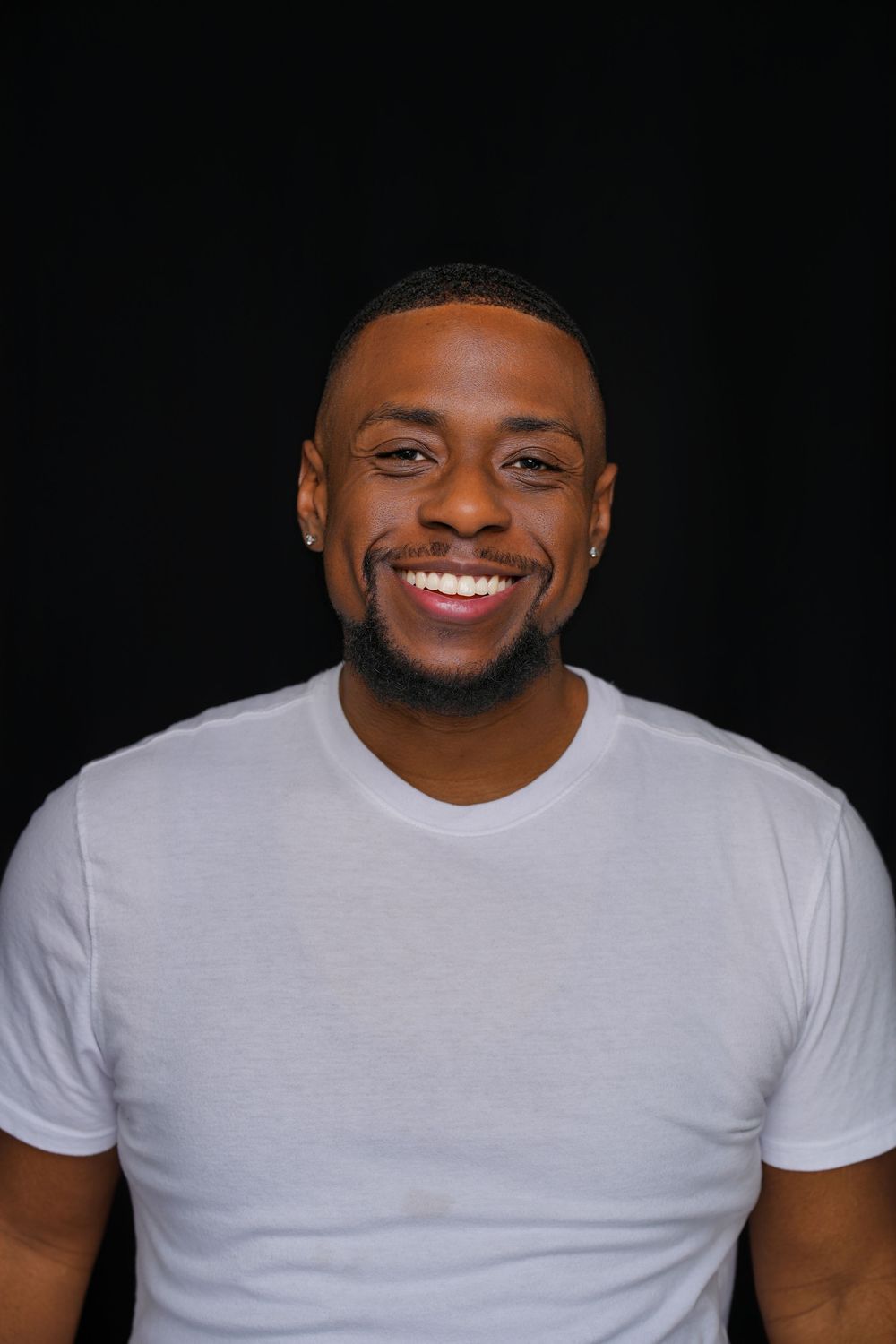 Close-up progression of someone in a white t-shirt smiling against a dark background.