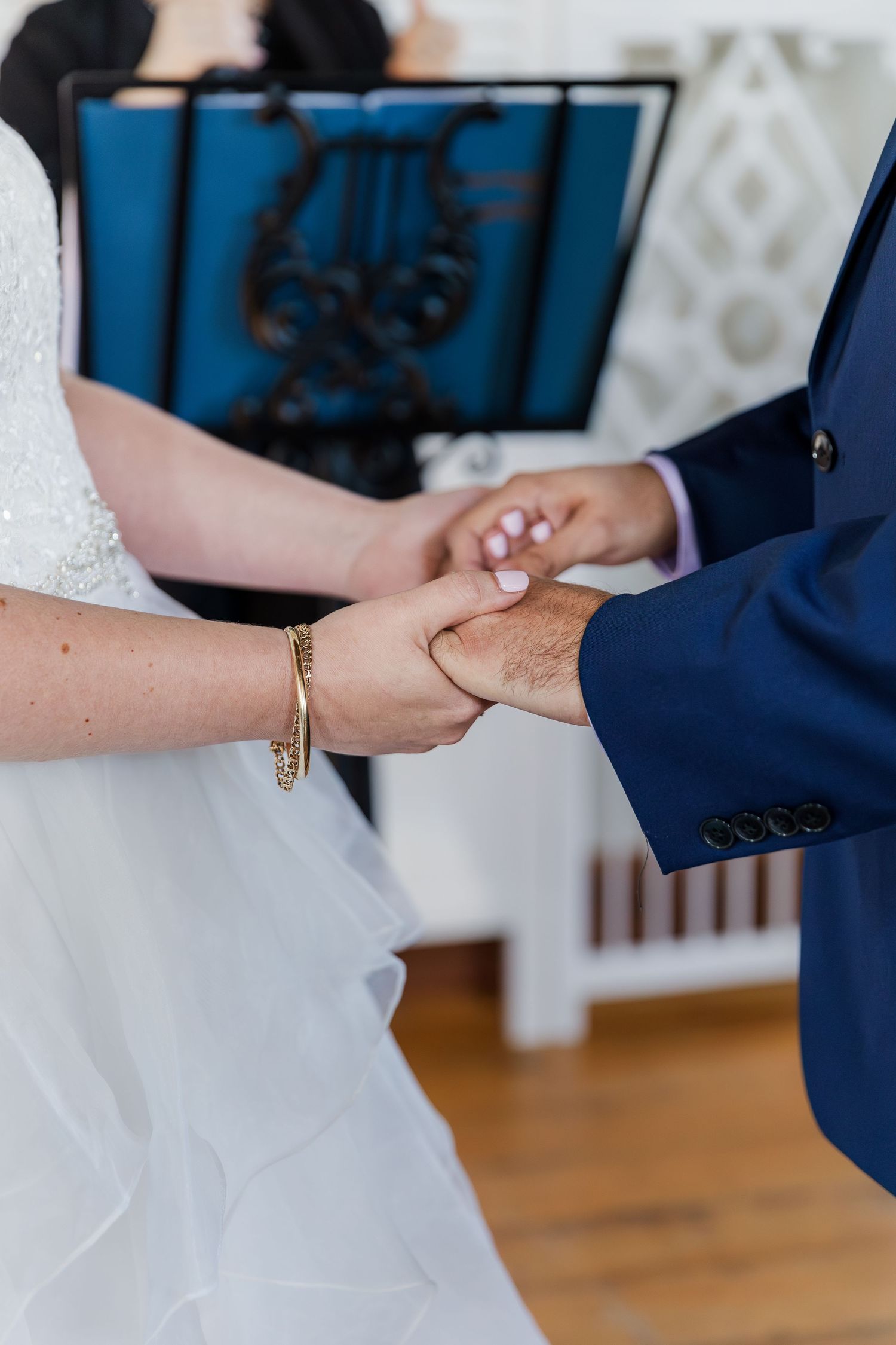Close up of bride and groom holding hands during wedding ceremony exchange at Hauser Hall in Kitchener, Ontario.
