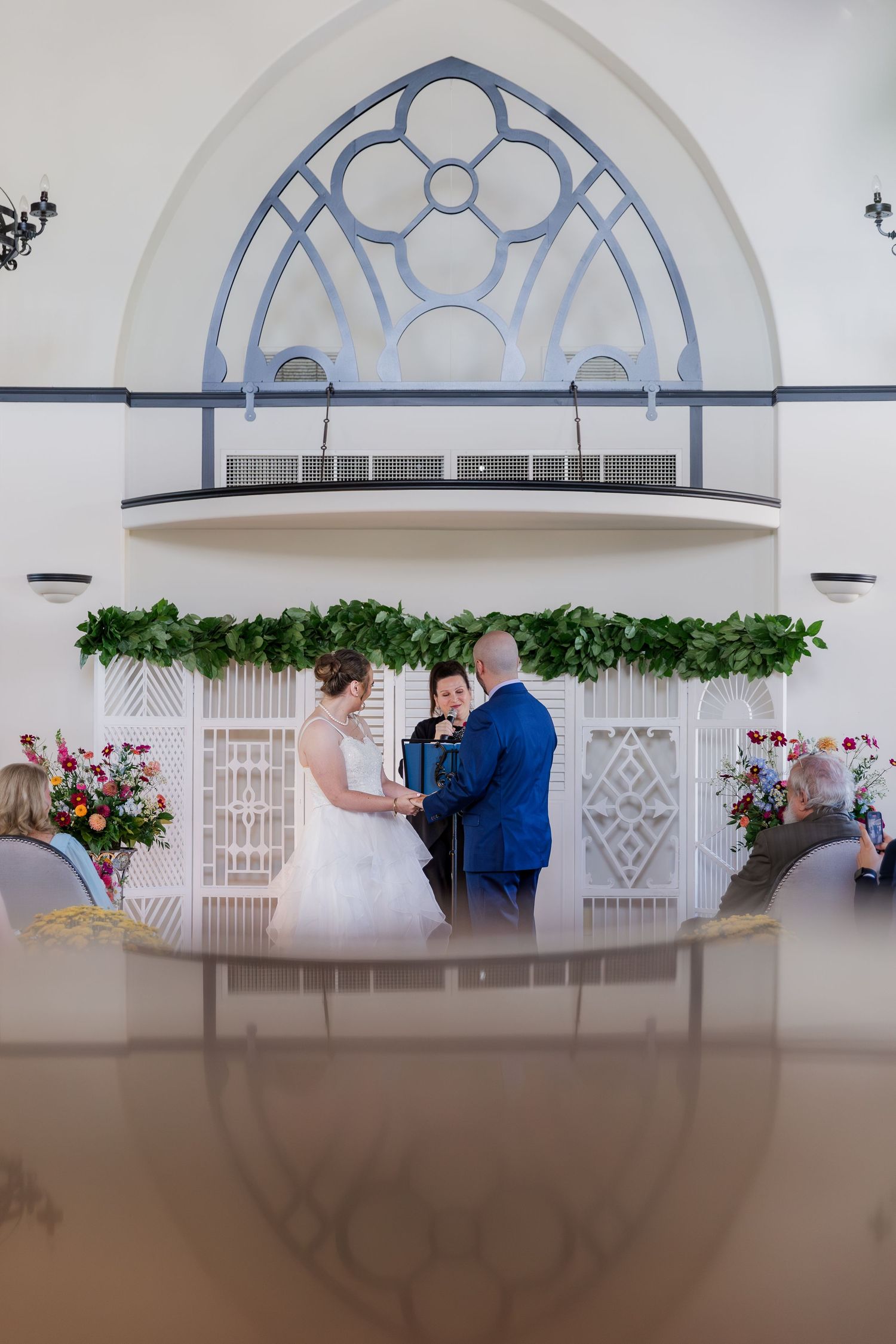 Bride and groom during wedding ceremony with decorative arch and floral garland decorations at Hauser Hall in Kitchener, Ontario.