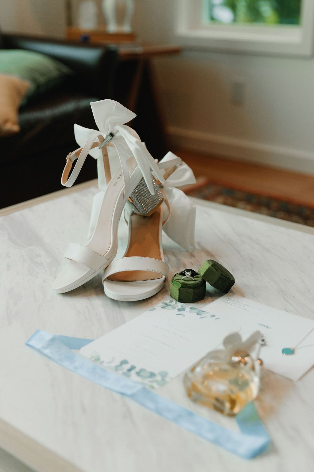 Wedding invitation details with watercolor accents and a green velvet ring box on a white surface.