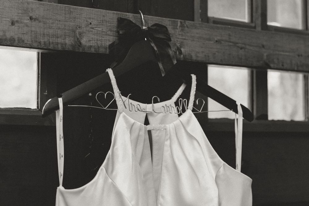 White wedding dress displayed against rustic wooden beams and natural lighting.