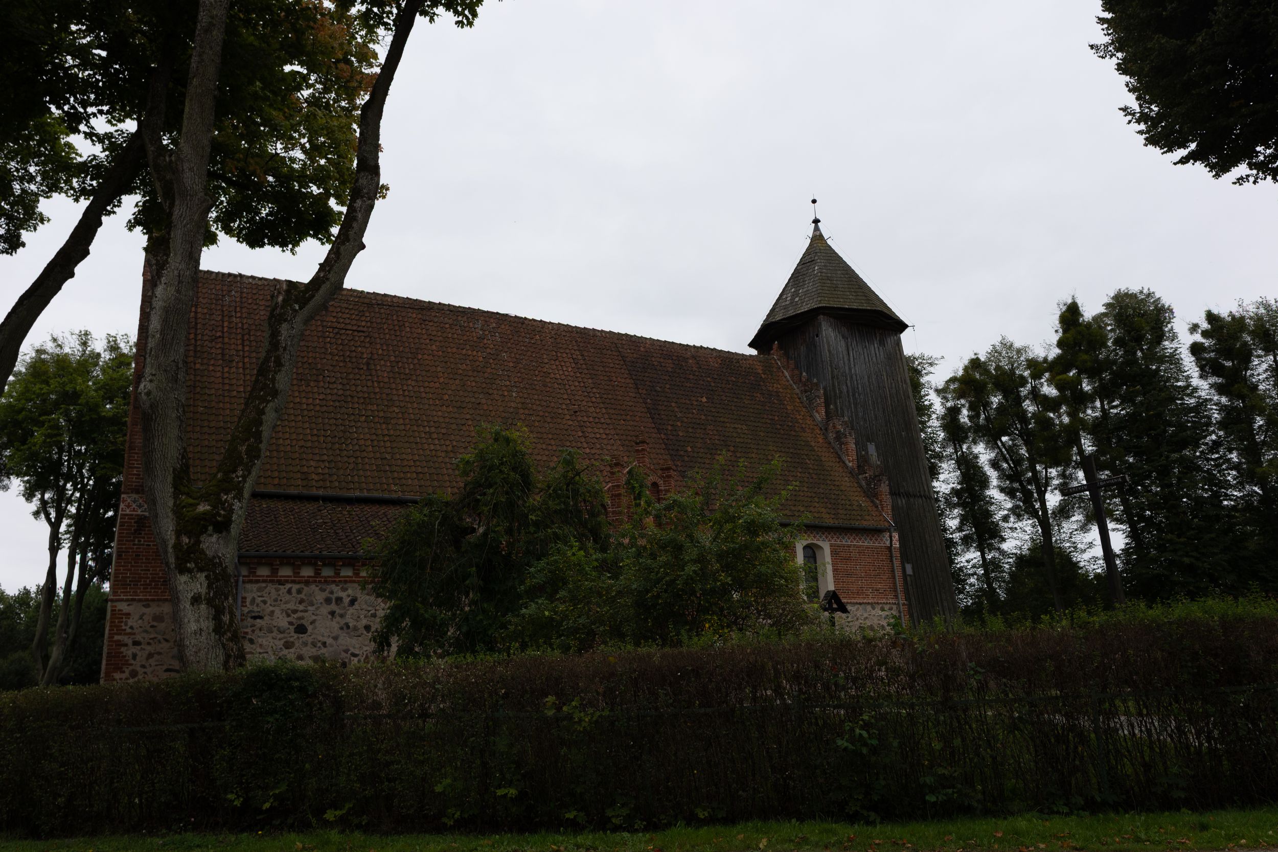 A scenic row of gothic church steeples and bell towers stands against a cloudy sky in a countryside landscape.