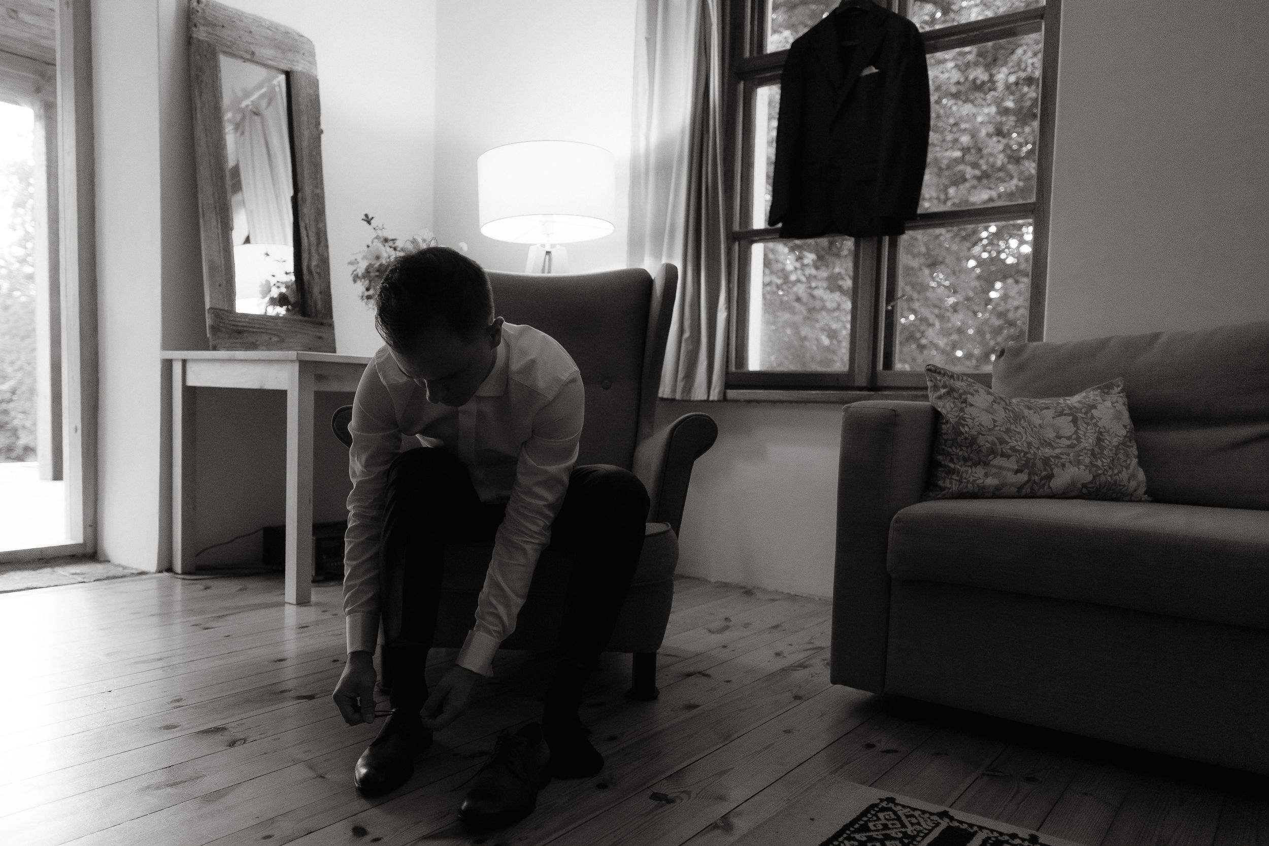 A person in dark clothing curled up in a corner of a room in a distressed position.