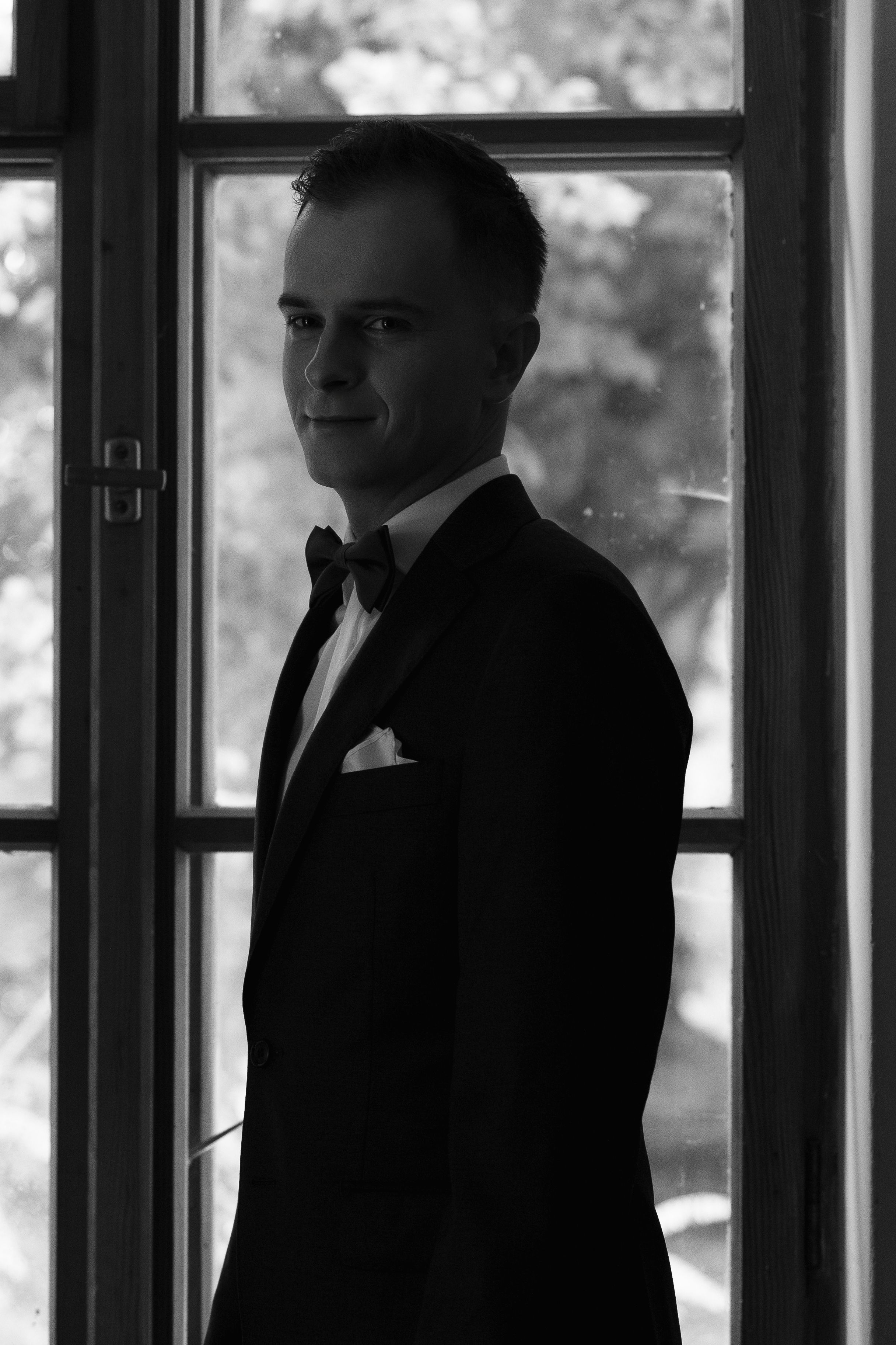 Silhouettes of business people in suits standing by windows in a dark interior hallway creating a dramatic atmosphere.