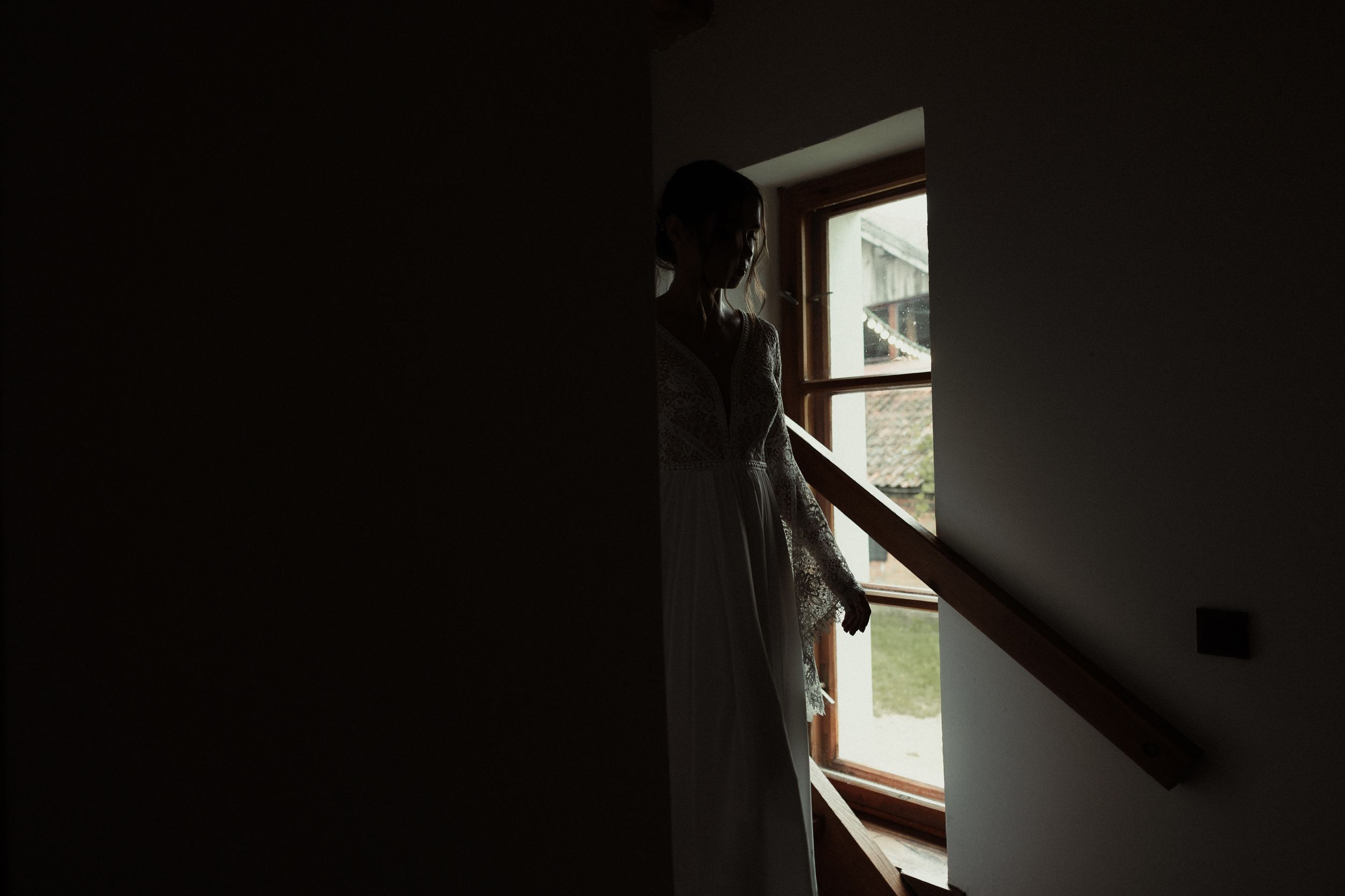 Dark silhouette of a person visibly illuminated through a window against moody lighting conditions.