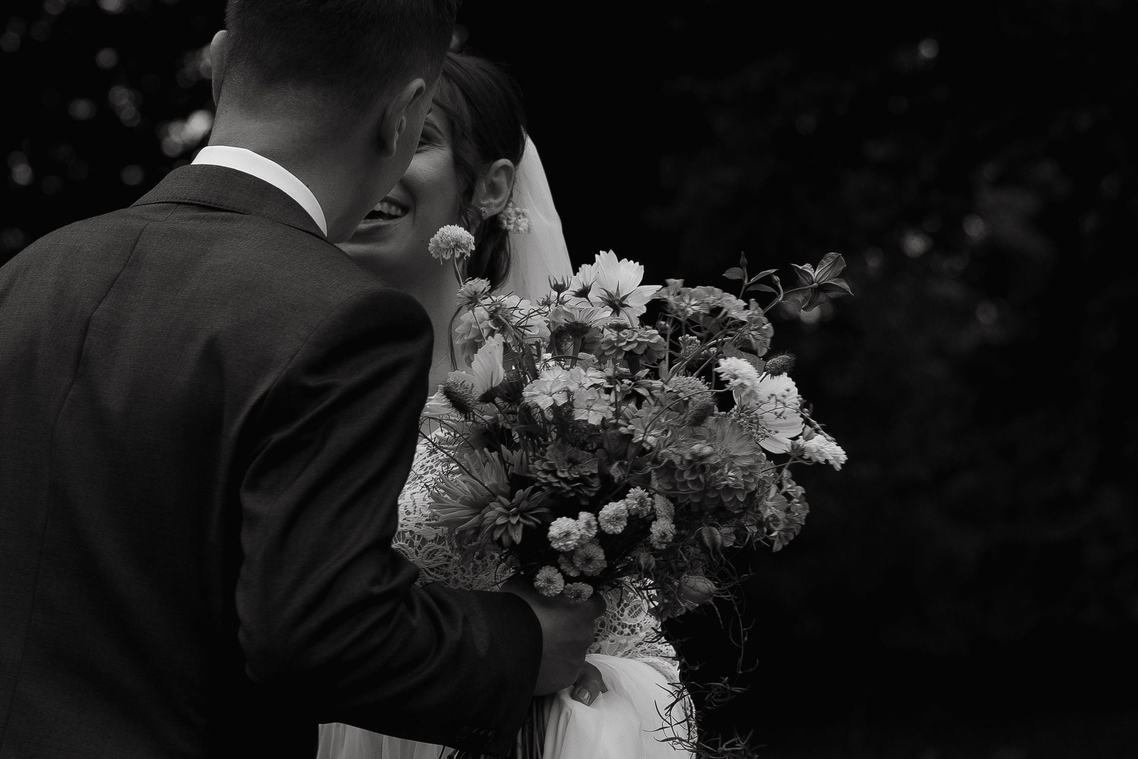 A romantic kiss between newlyweds at a wedding ceremony with decorative floral arrangements in the background.