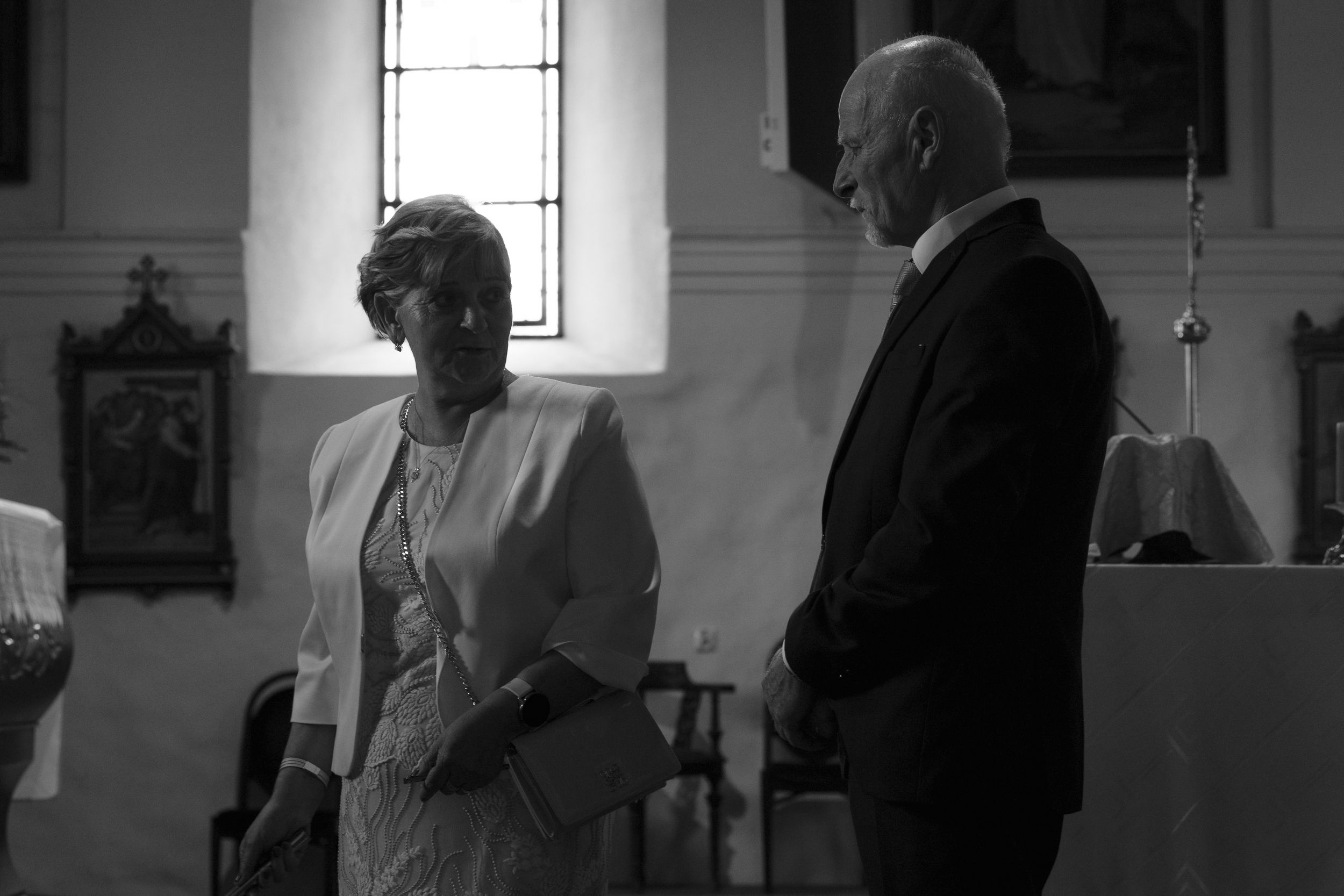 Black and white image capturing intimate moments during a wedding ceremony in a traditional chapel.