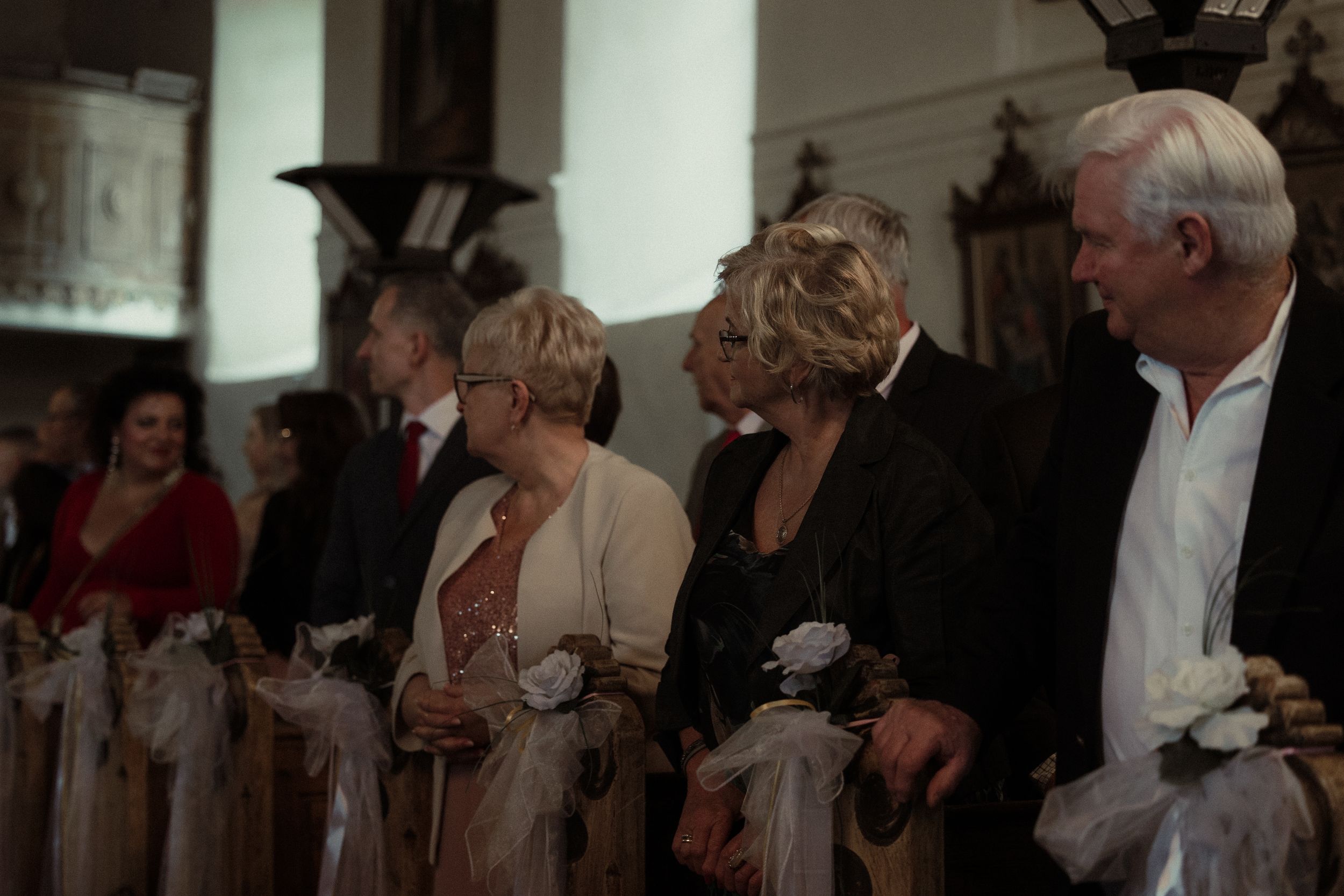 Wedding guests in formal attire mingle and dance during an evening reception celebration.