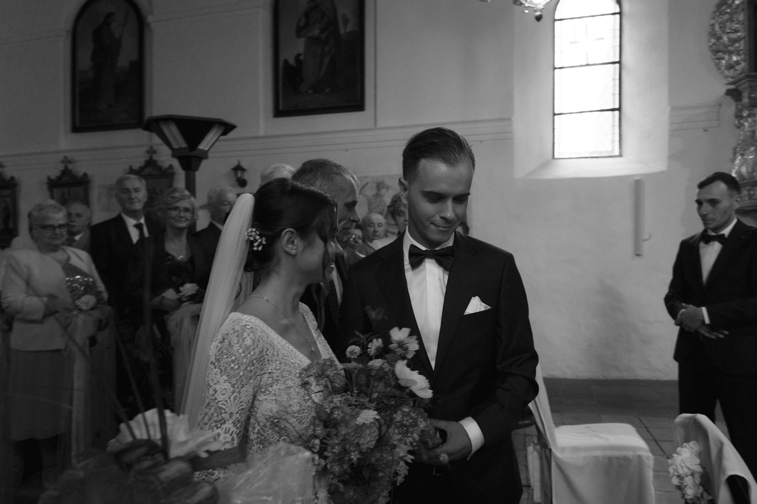 Elegant black and white wedding ceremony photo in historic church with decorative details.