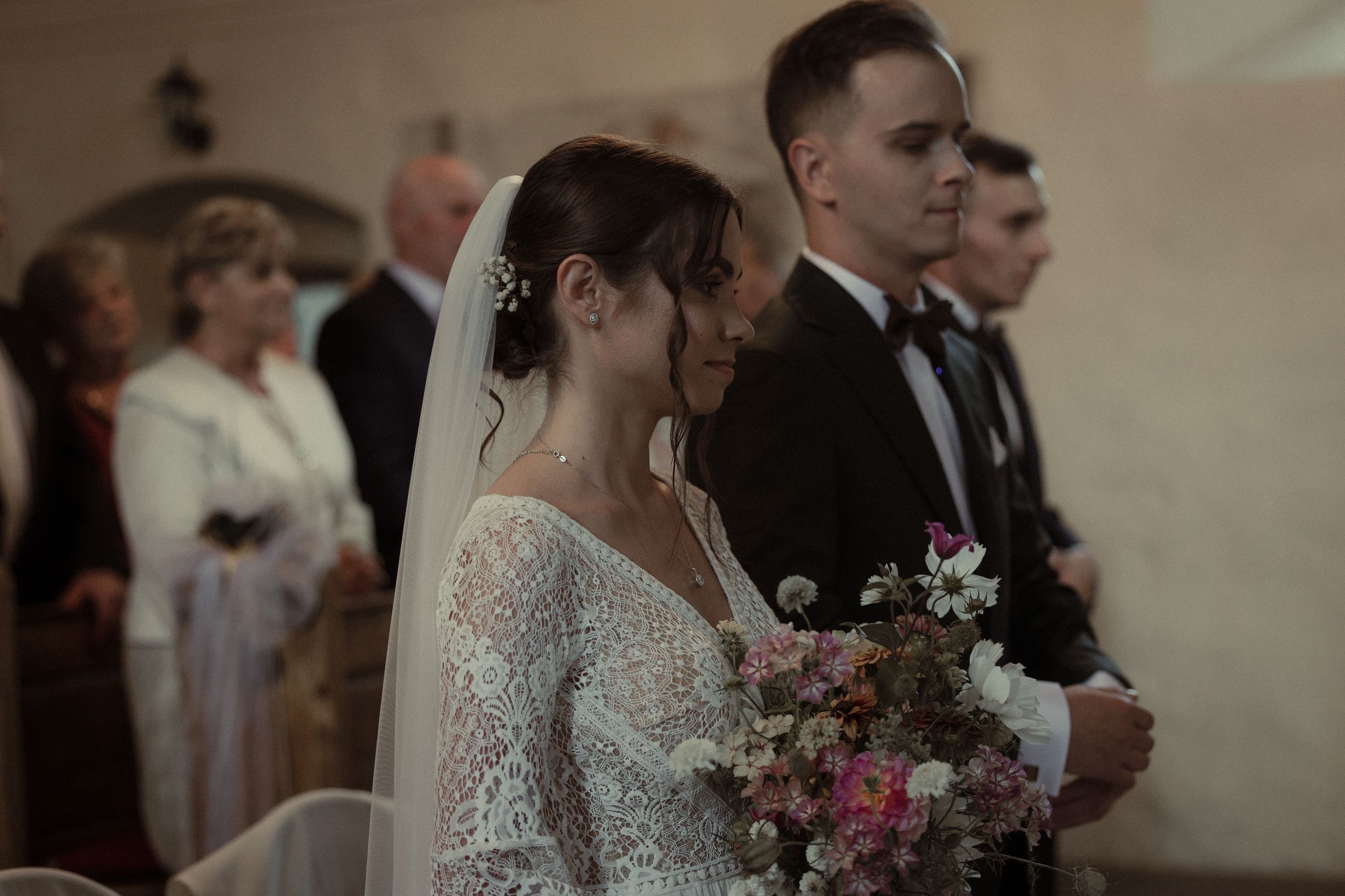 Wedding party with pink bouquets and lace dresses mingles during elegantly styled reception celebration.