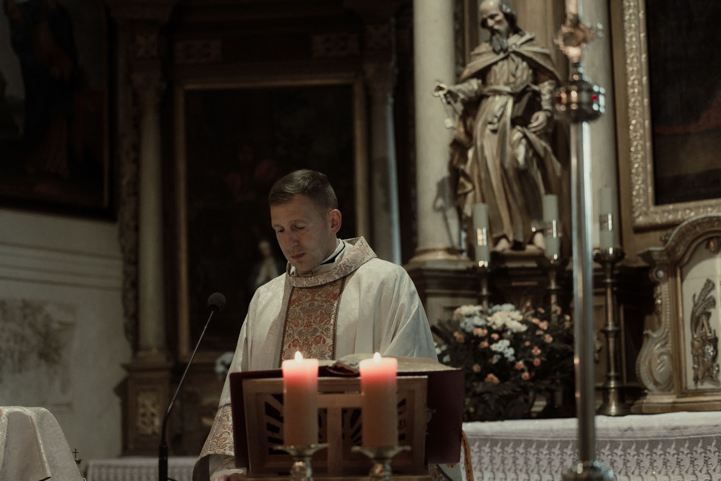 Candlelit church altar decorated with flowers and religious imagery.