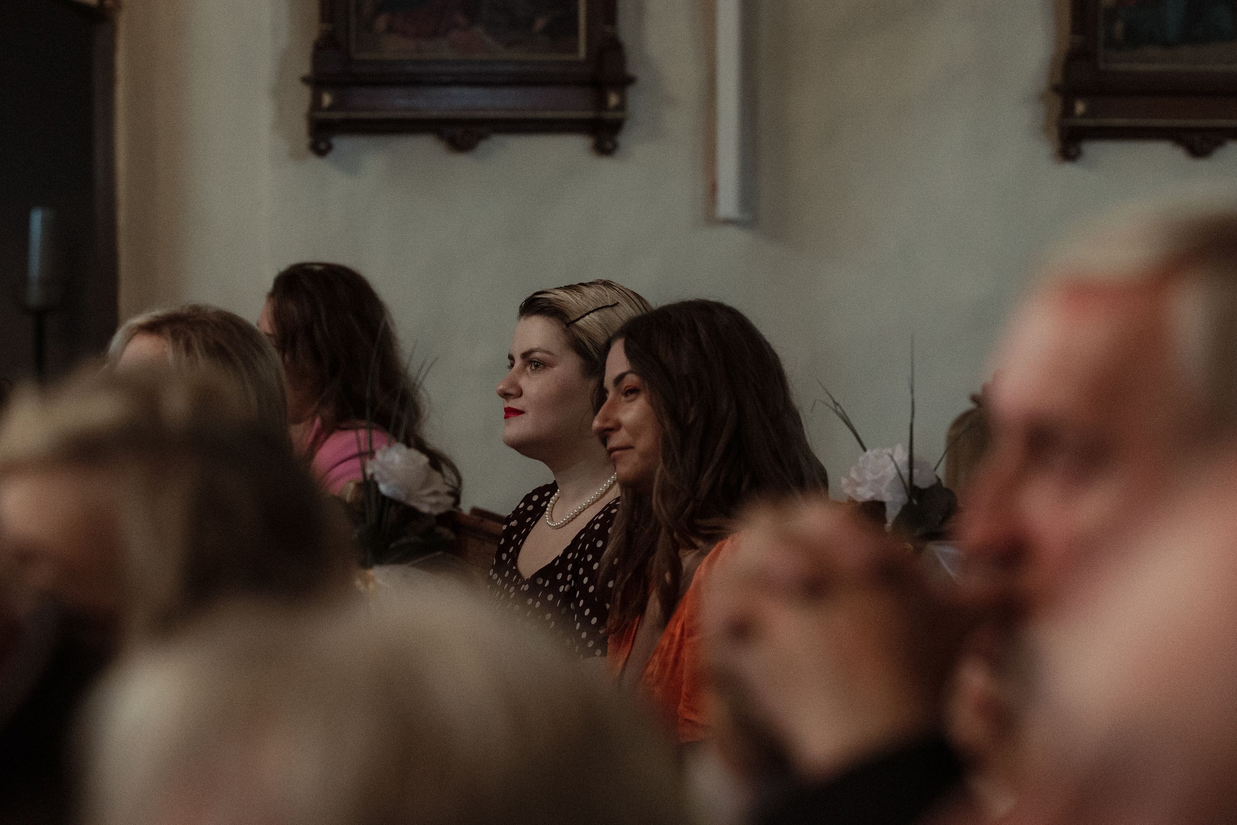 Crowd watching a performance in a dimly lit indoor venue with traditional wooden decor and candles on the walls.