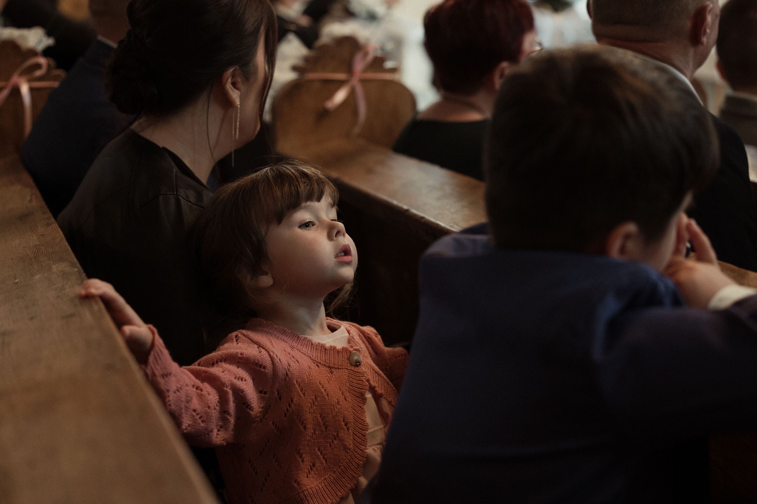 Concert audience members sit in rows at a live performance venue with soft lighting creating an intimate atmosphere.