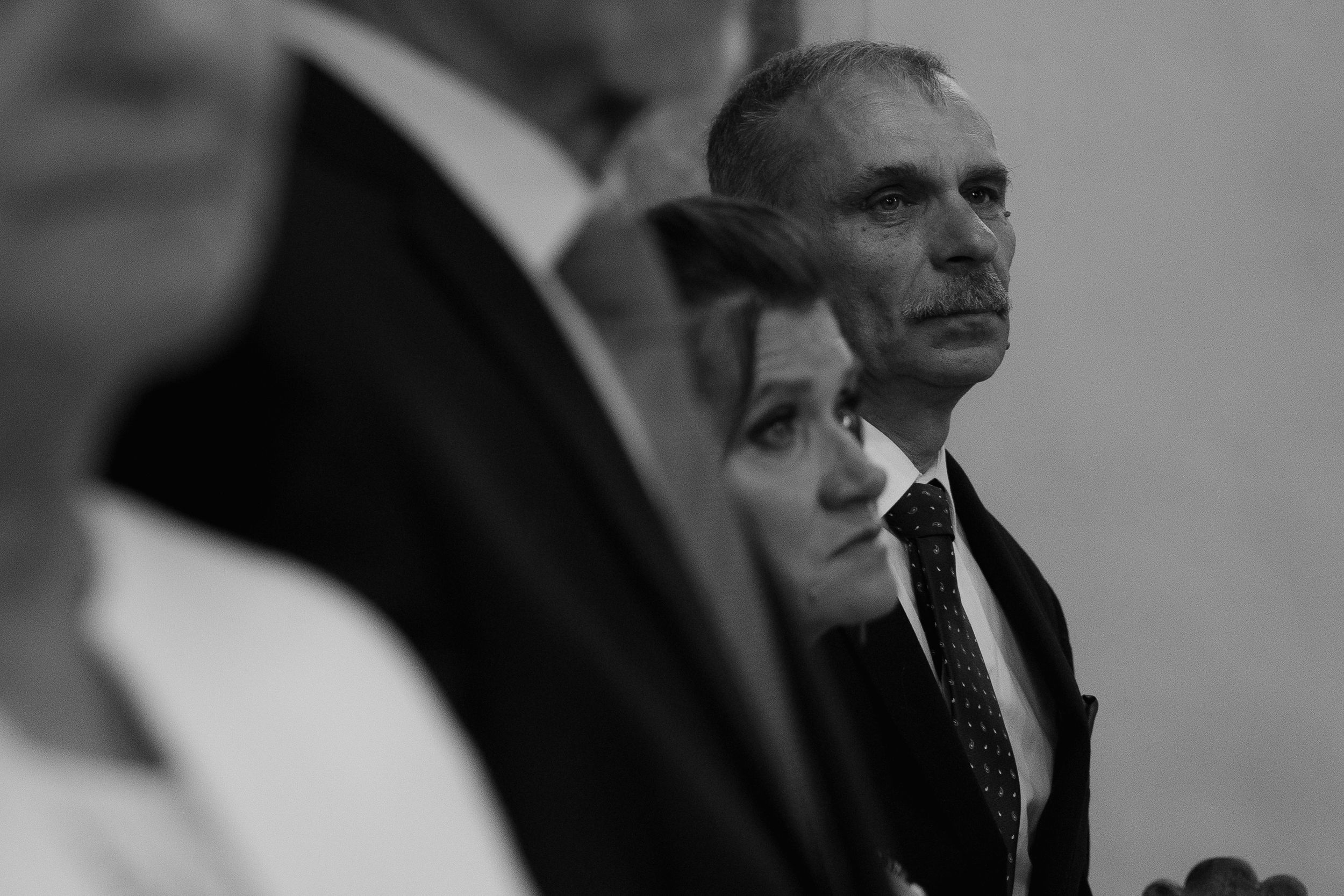 A black and white profile view showing a person wearing formal business attire in a meeting setting.