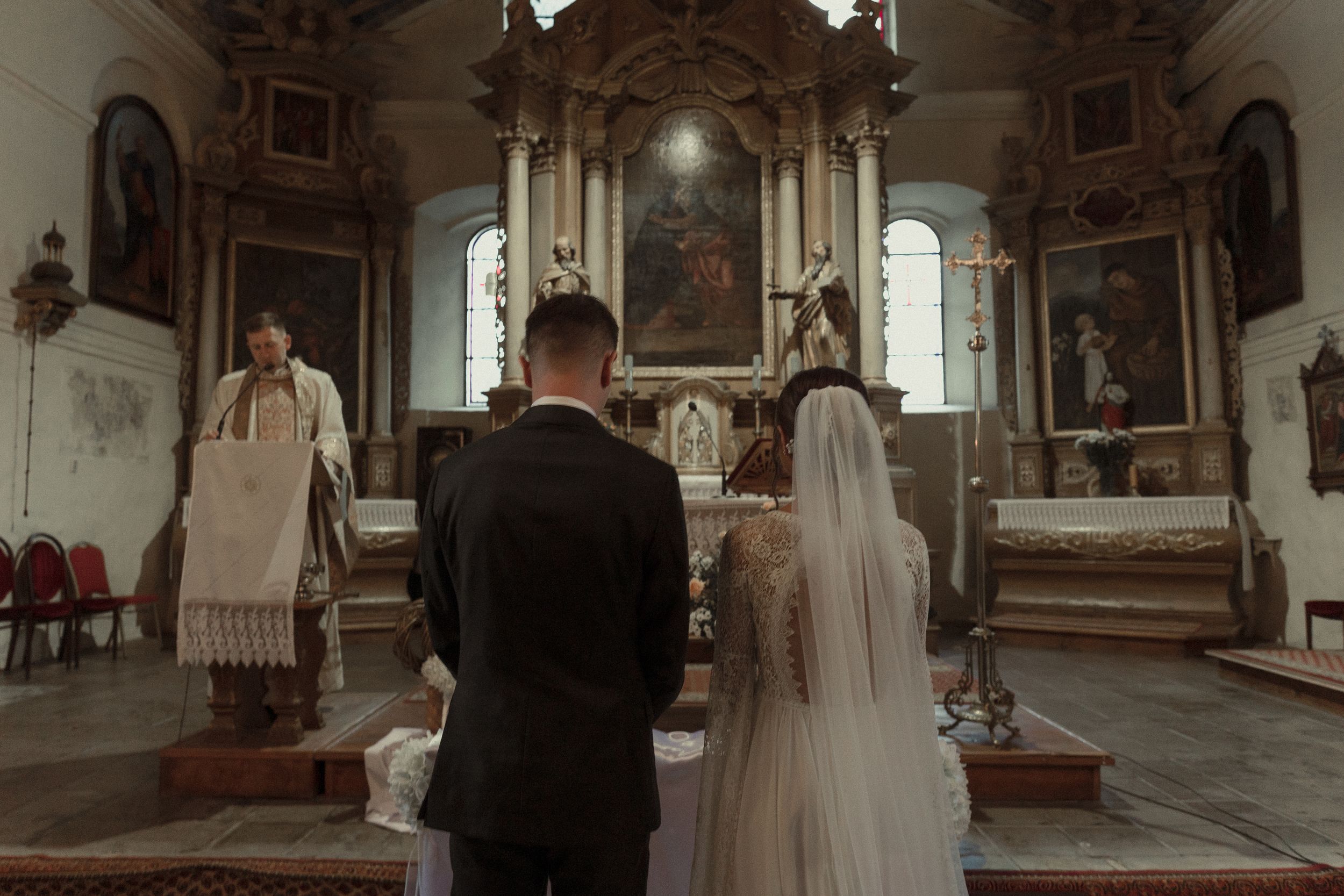 A romantic wedding ceremony taking place inside a historic church with ornate architectural details and ambient lighting.