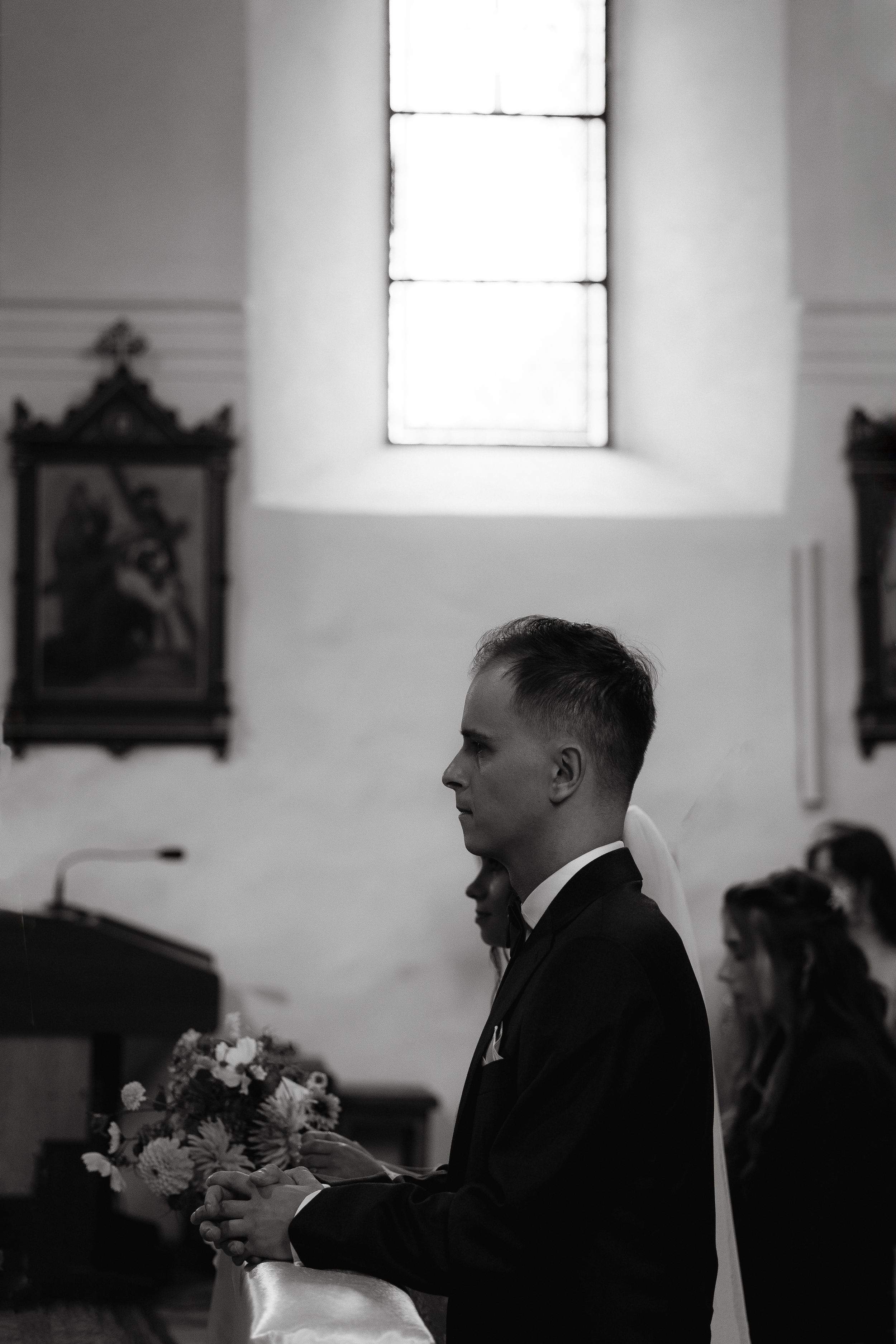 Black and white interior church scene with attendees sitting in pews during a religious service.