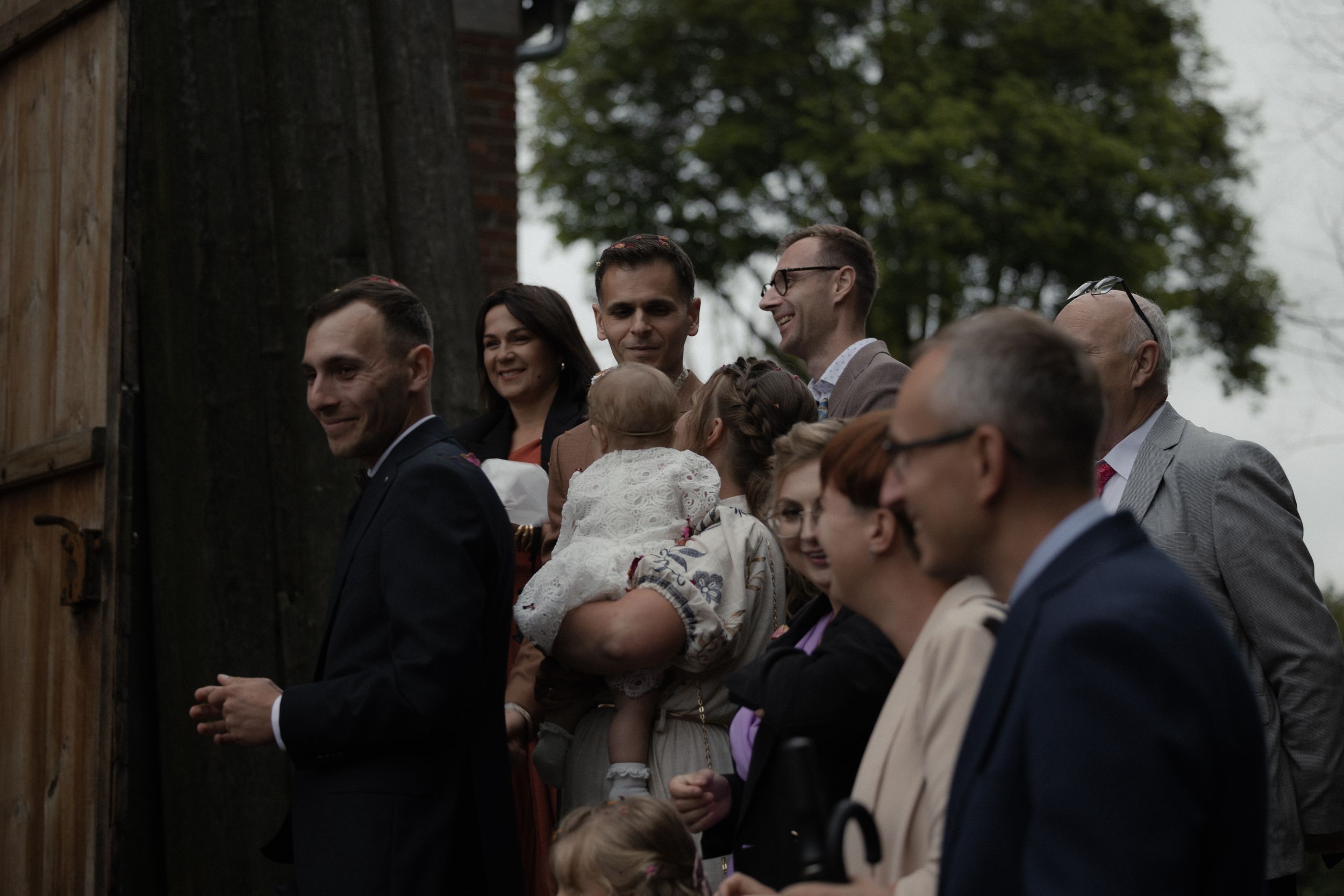 Large group of suited guests socializing outdoors at a formal gathering event.