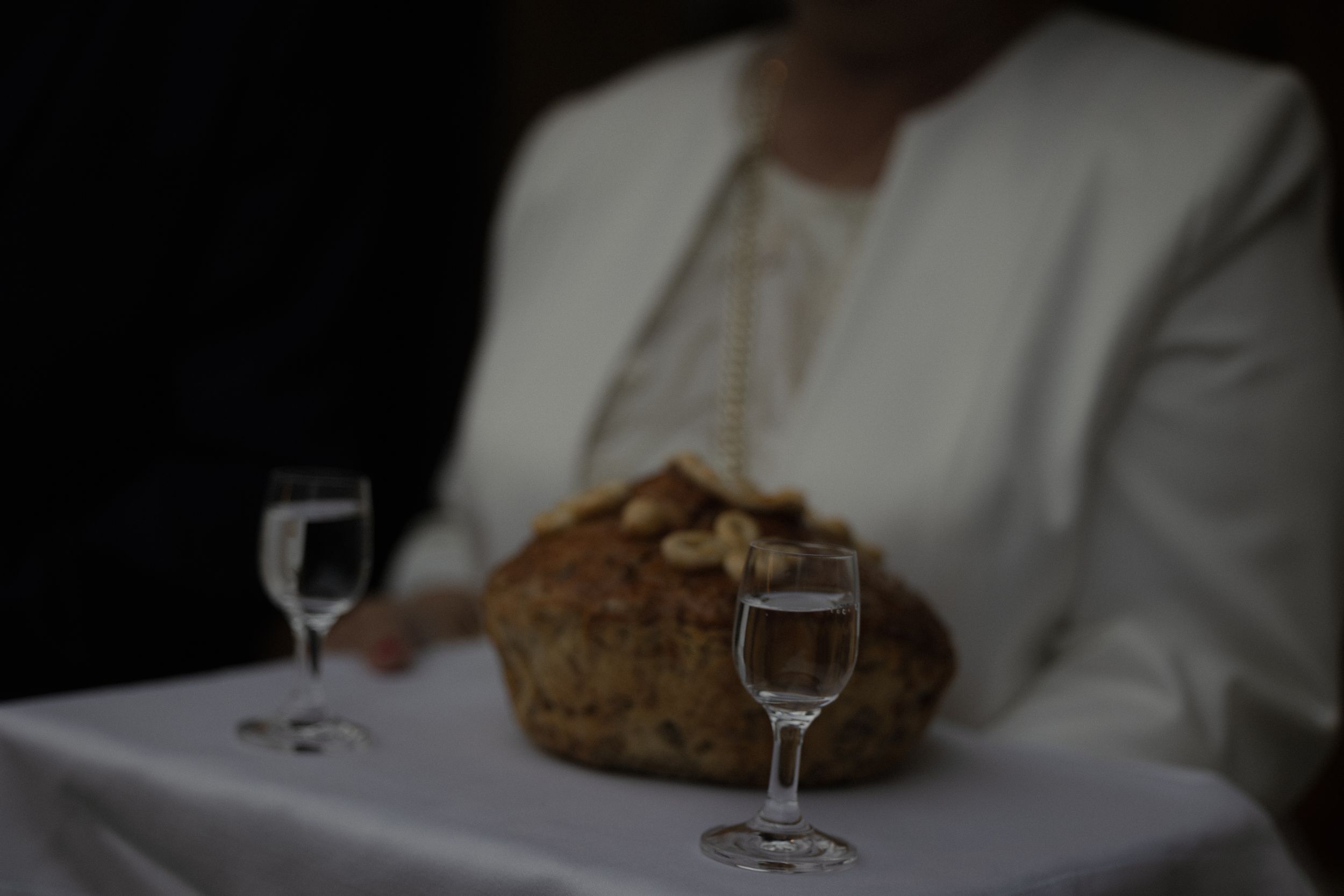 Wine glasses and bread are elegantly arranged on white tablecloths in an upscale restaurant dining setting.