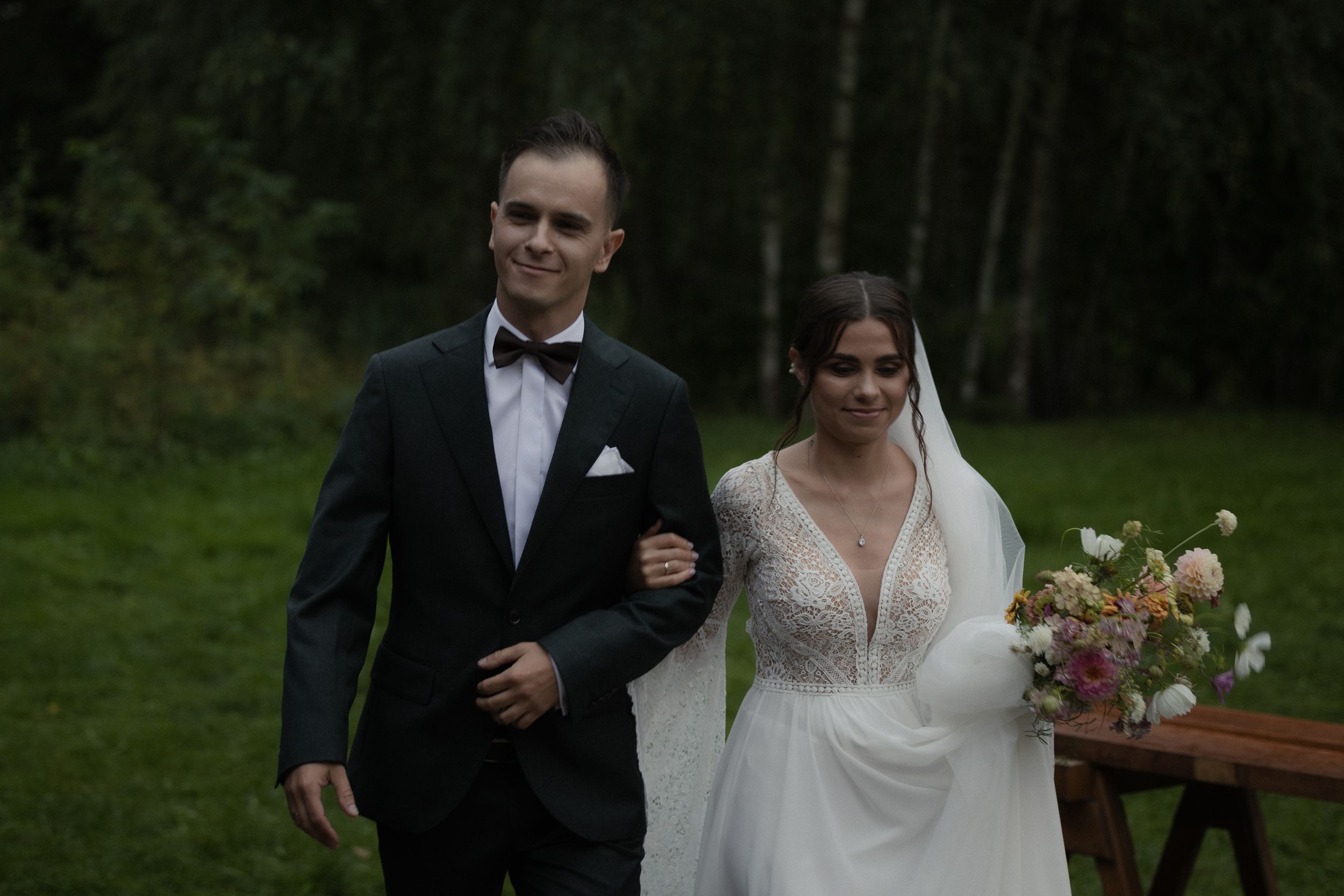 A wedding couple walks through a beautiful forested area during their outdoor photo session.