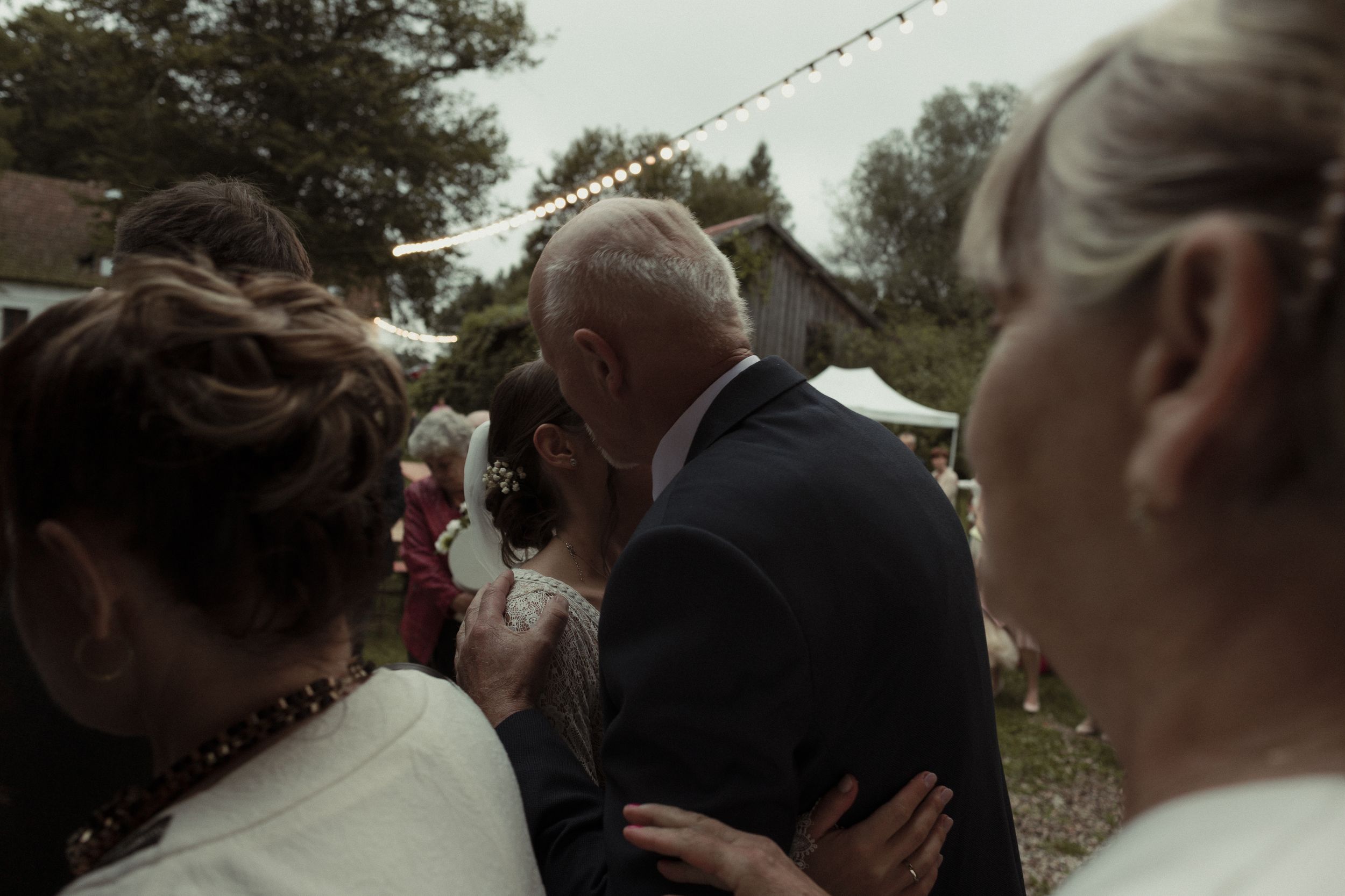 People gathered at an outdoor event sharing an intimate moment on an overcast day.