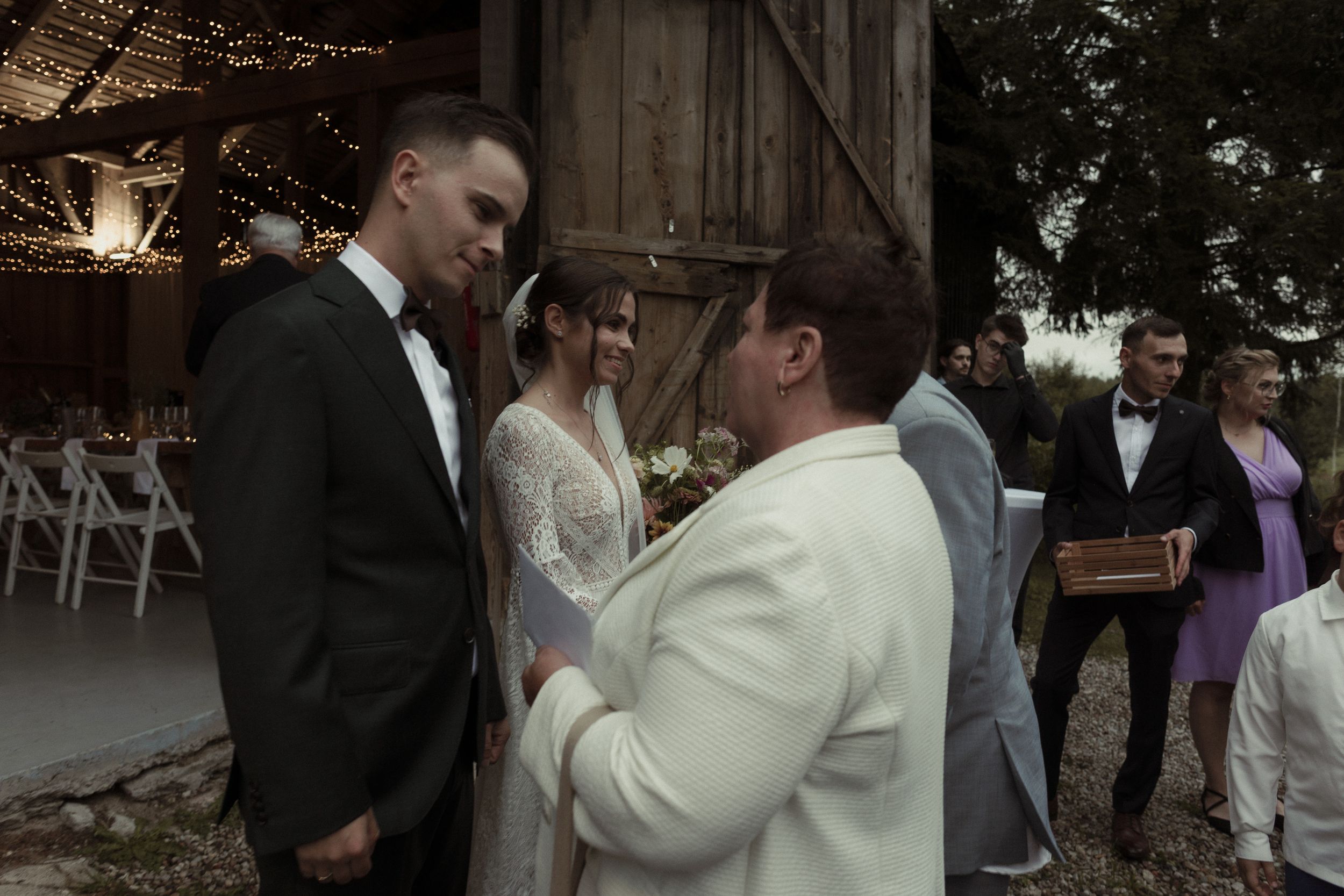 Wedding couple and guests sharing joyful moments during outdoor evening celebrations in black and white photograph.