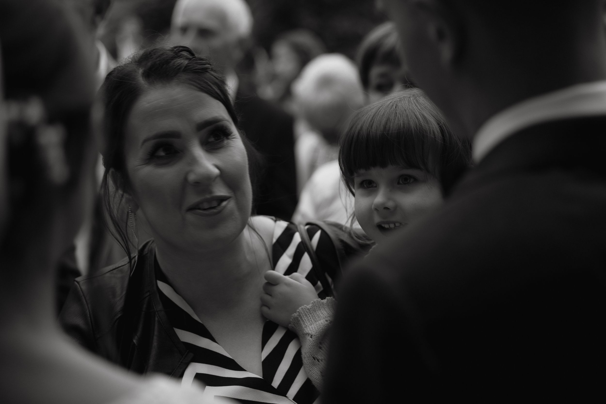 Black and white photo showing two smiling people attending a social gathering at a formal event.
