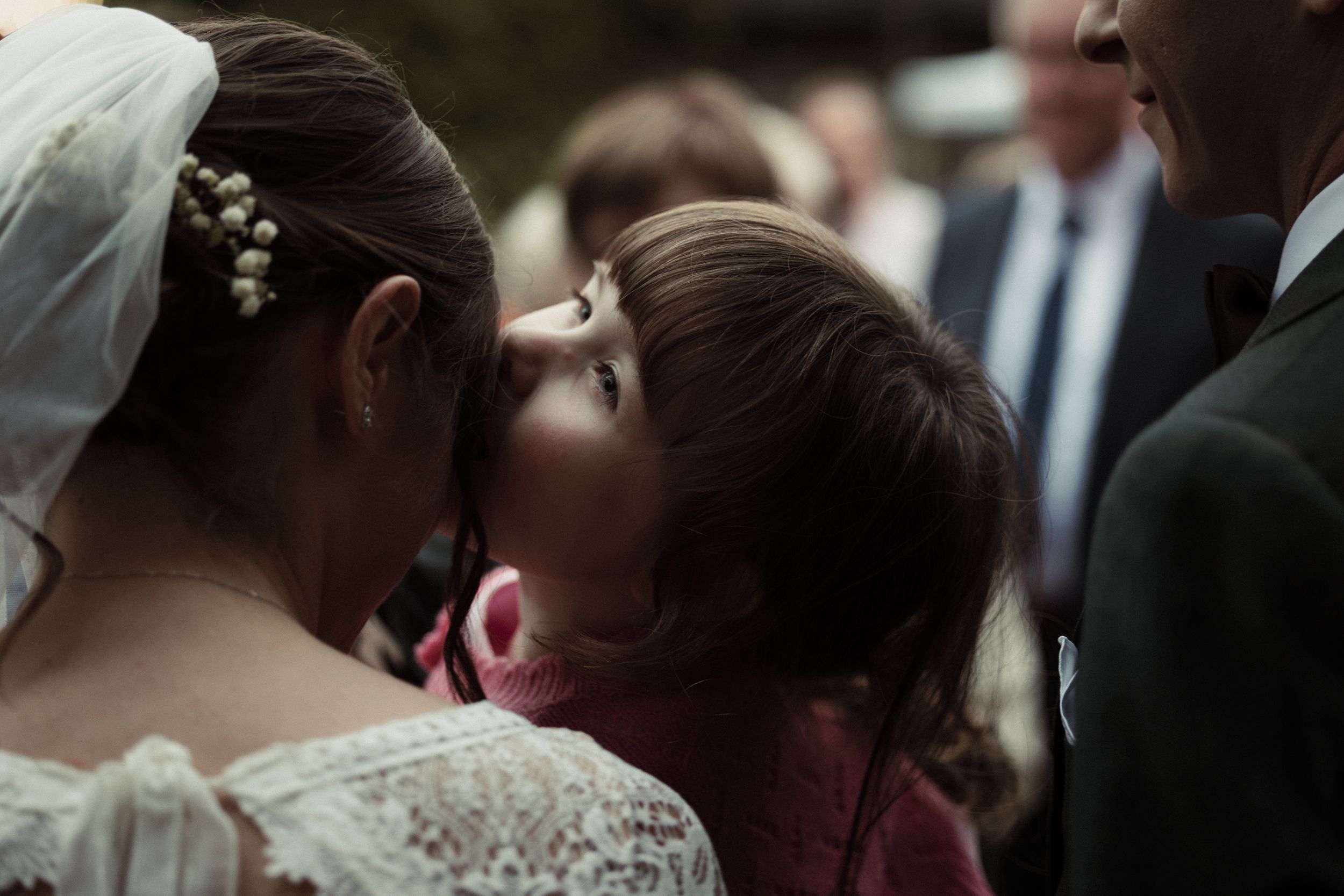 A wedding ceremony with guests standing together in a formal setting as the couple exchanges vows.