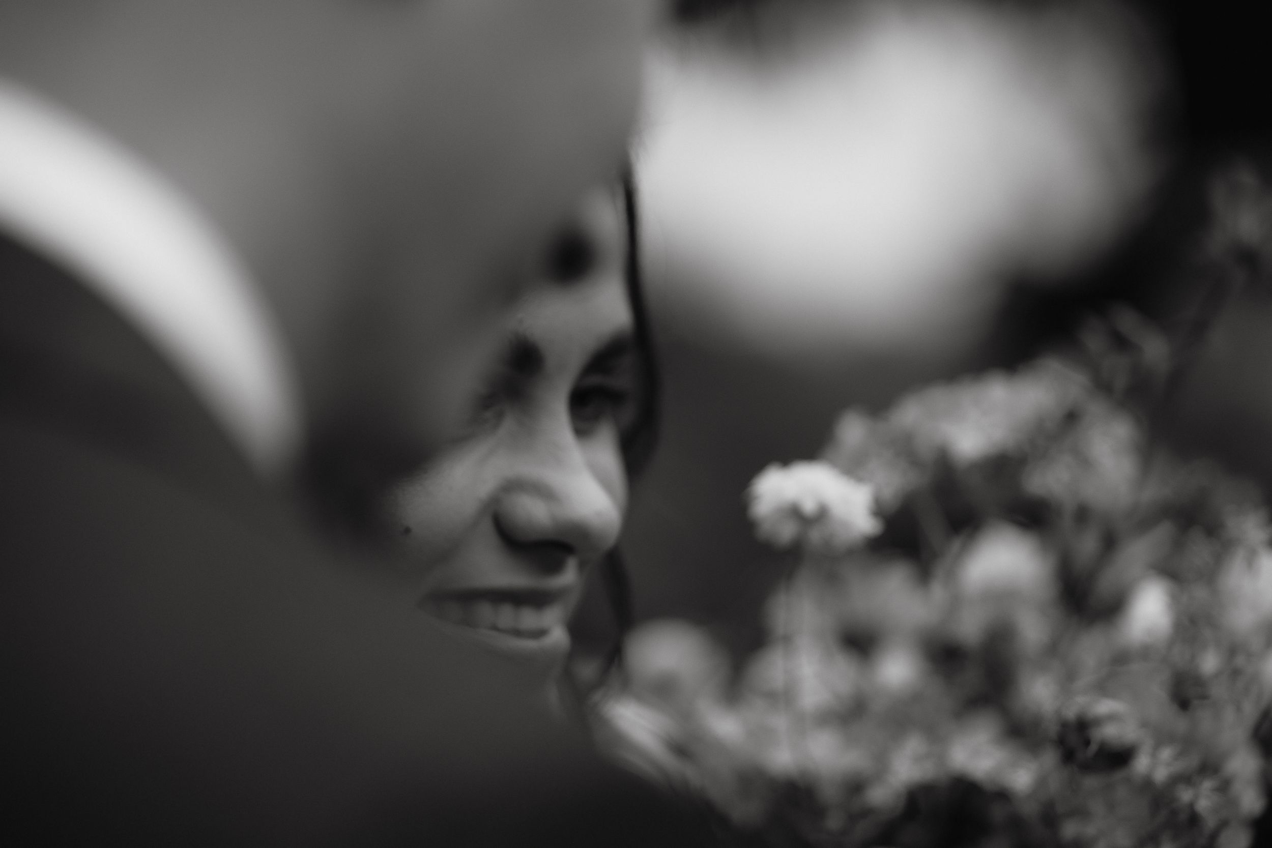 Black and white artistic portrait showing an intimate moment between two people at a wedding ceremony in nature.