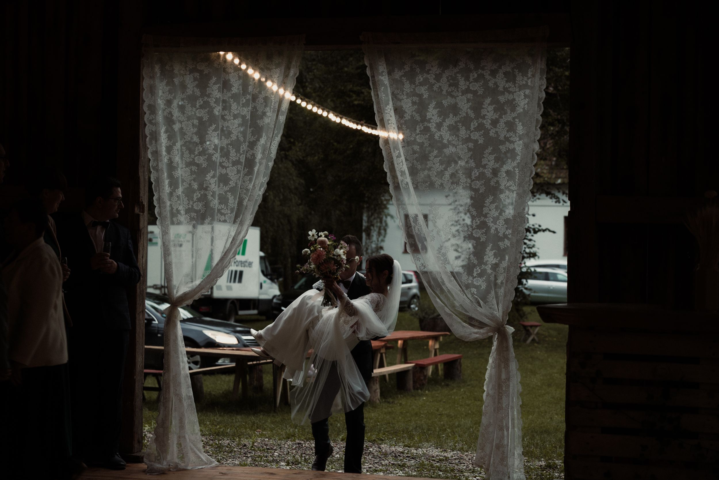 A romantic wedding altar decorated with flowing white drapes and floral arrangements in an outdoor garden setting.