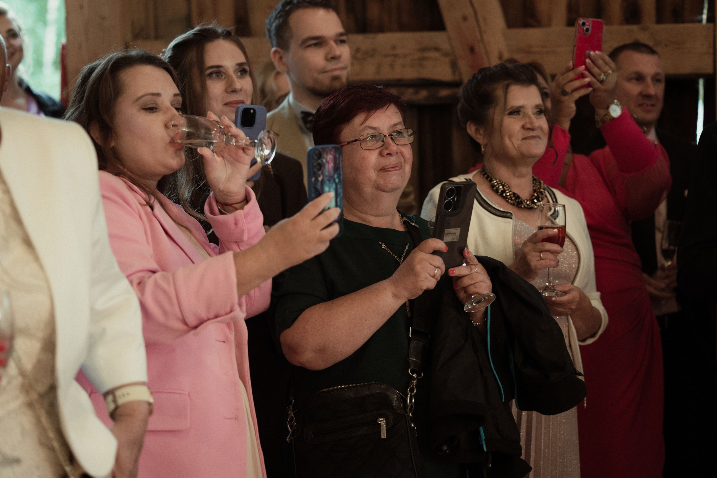 People in formal attire raise their glasses in a celebratory toast during an indoor event.
