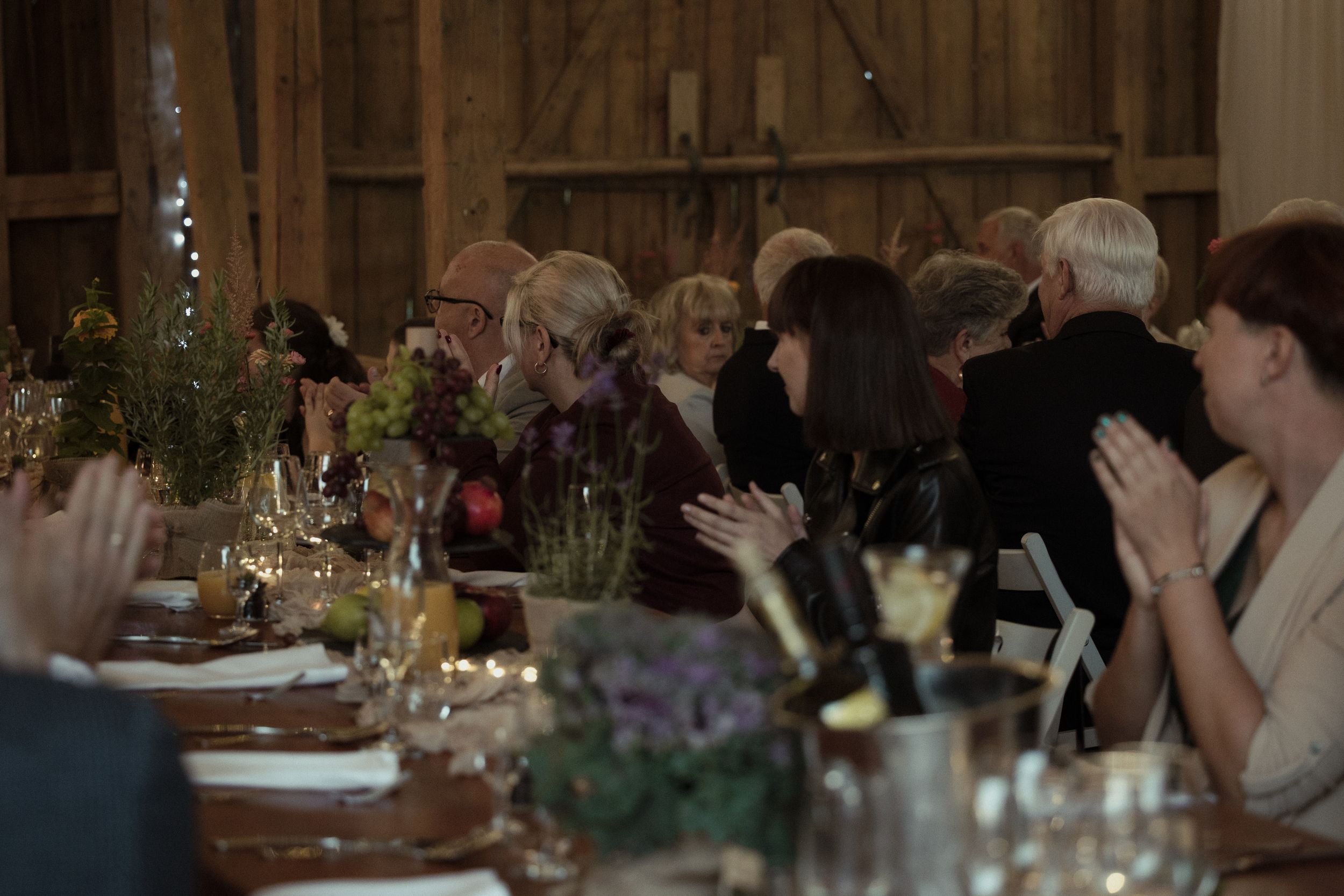 Candid group dinner scene with diners seated at long tables in an elegant, warmly lit restaurant interior.