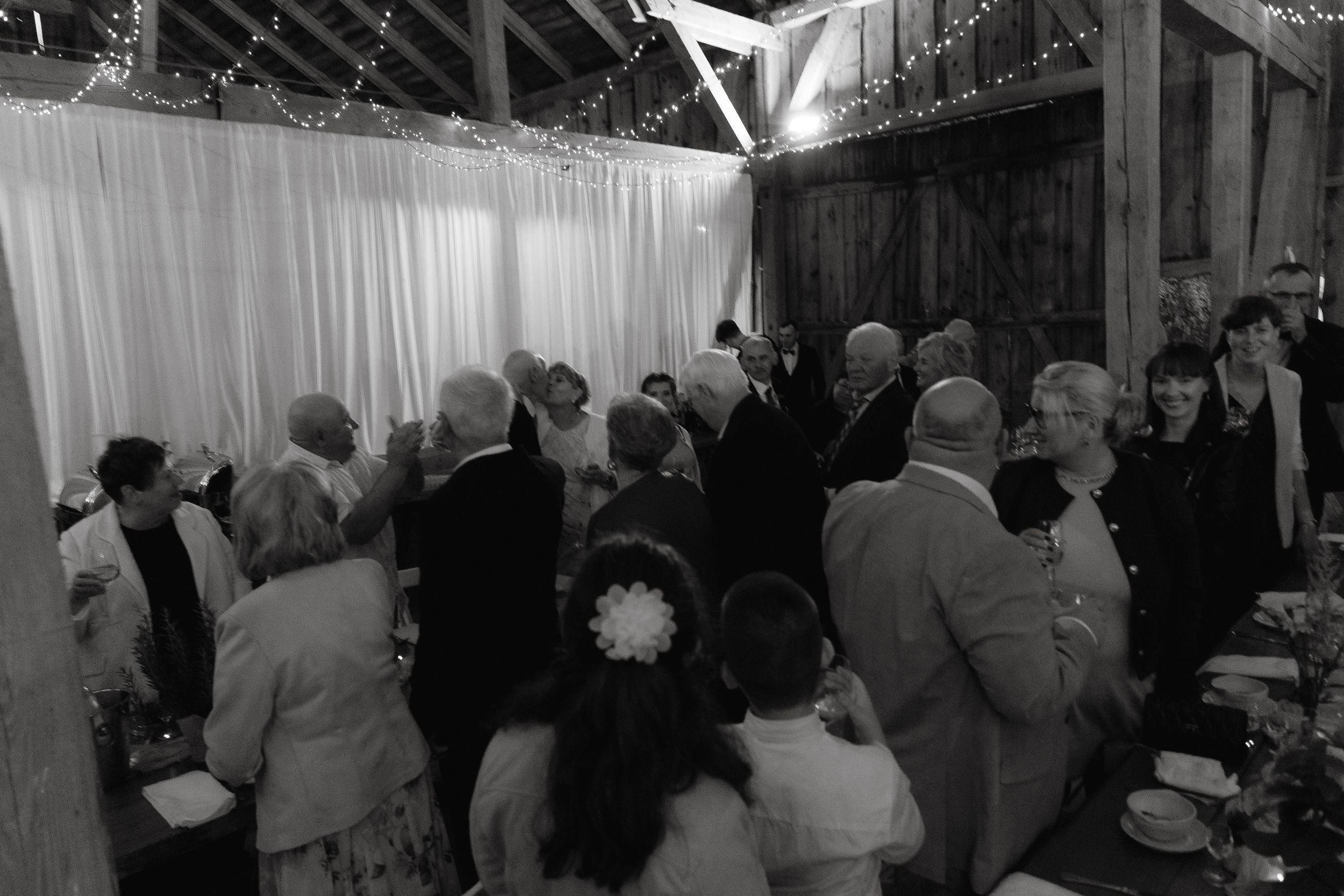 A crowd of people gathered in a low-light indoor space with high ceilings and exposed beams.