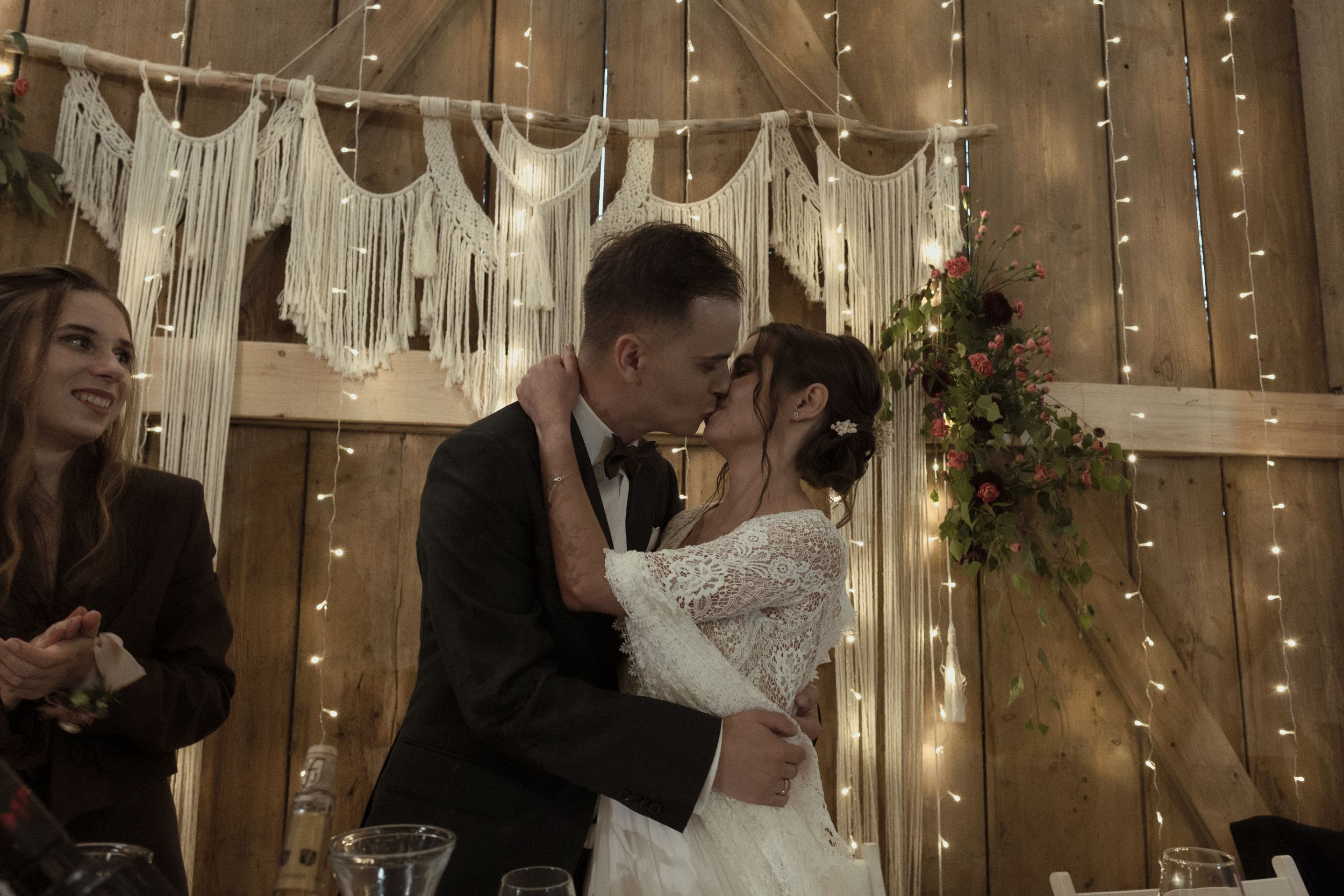 A wedding couple shares their first dance surrounded by warm string lights and shimmering curtains at their reception.