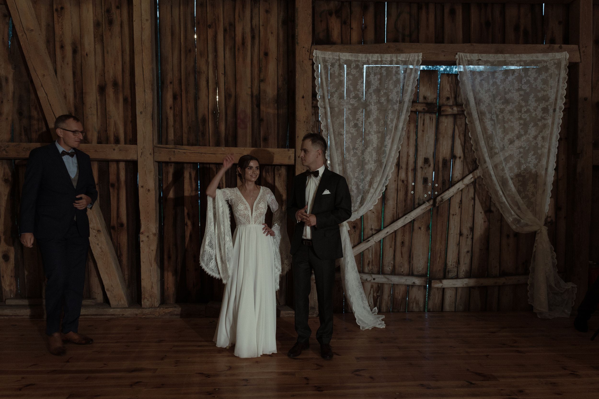 A rustic barn wedding reception with dancing couples illuminated by soft lighting and wooden walls.