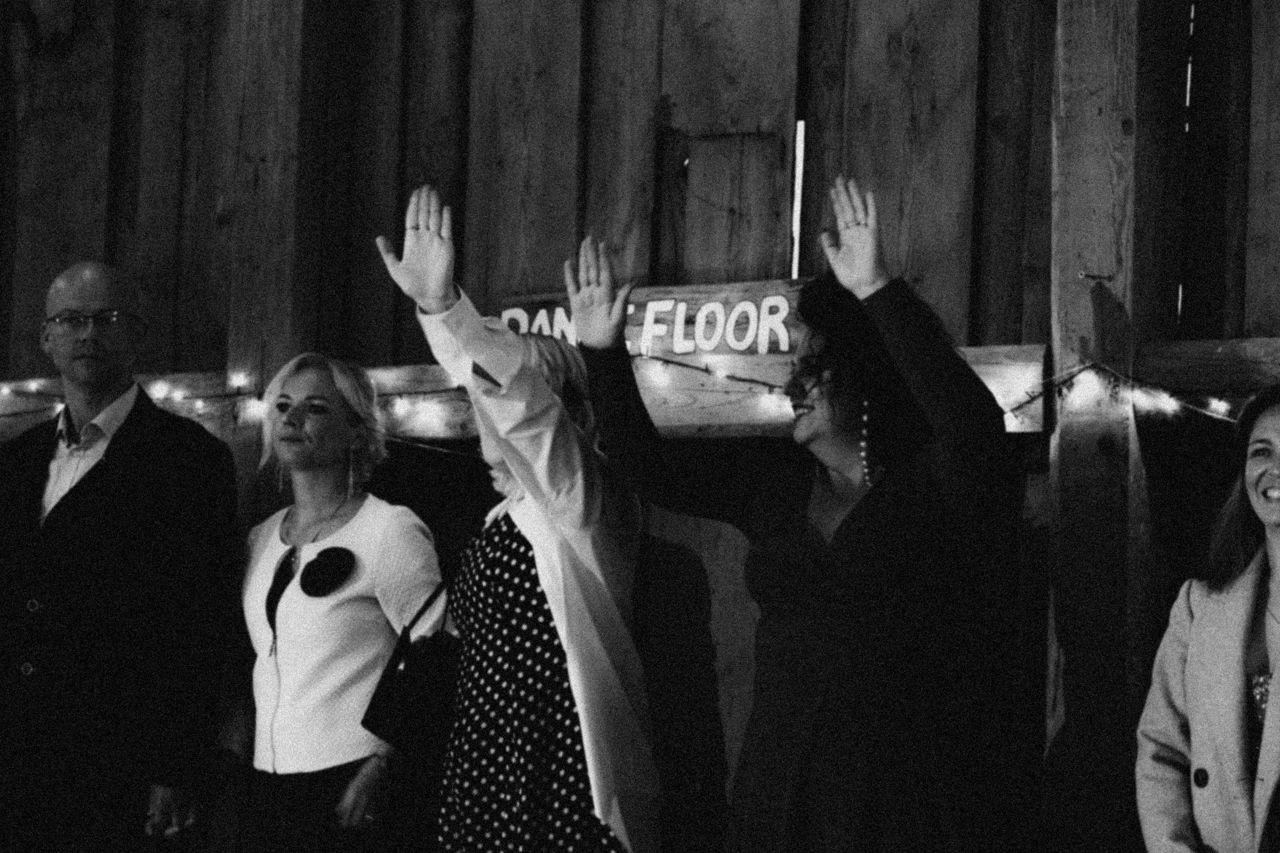 Group of dancers in black and white formal attire performing in dim lighting on stage during an event.
