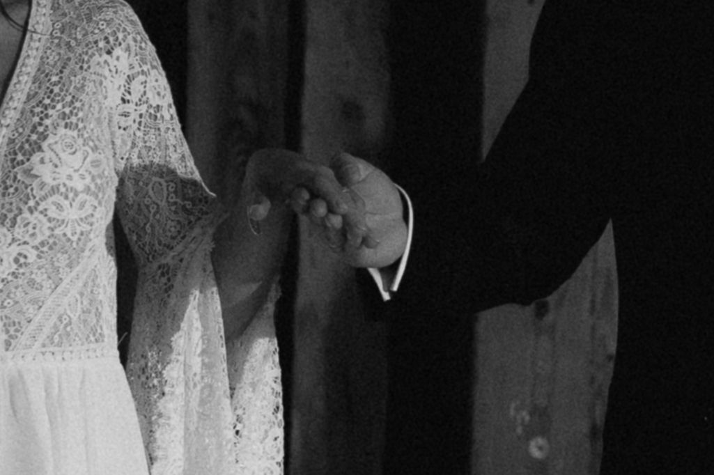 Dancing couple holding each other close during their first dance at an elegant black and white wedding reception.