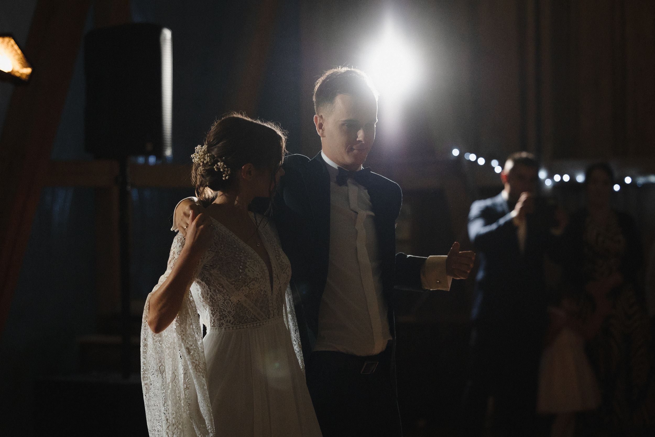 A wedding couple dances together during their first dance at their reception, illuminated by soft glowing lights.