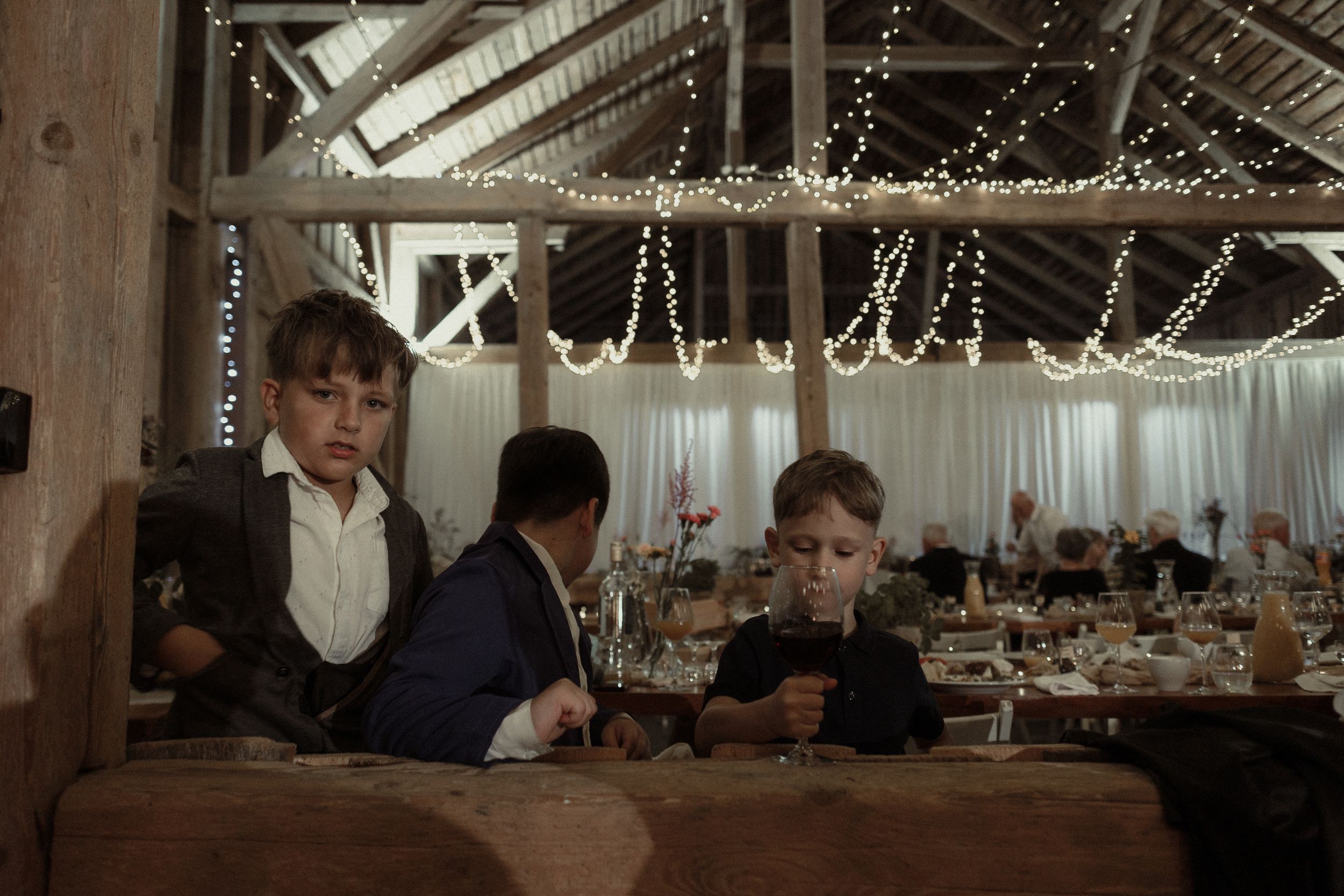 Wedding venue interior with rustic wooden beams and elegant crystal chandeliers glowing warmly.