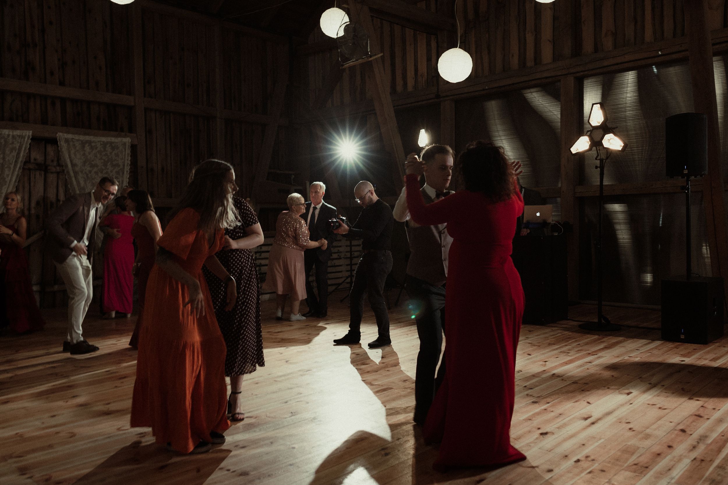 A large dance floor illuminated by spotlights with several dancers in flowing red dresses during a performance.