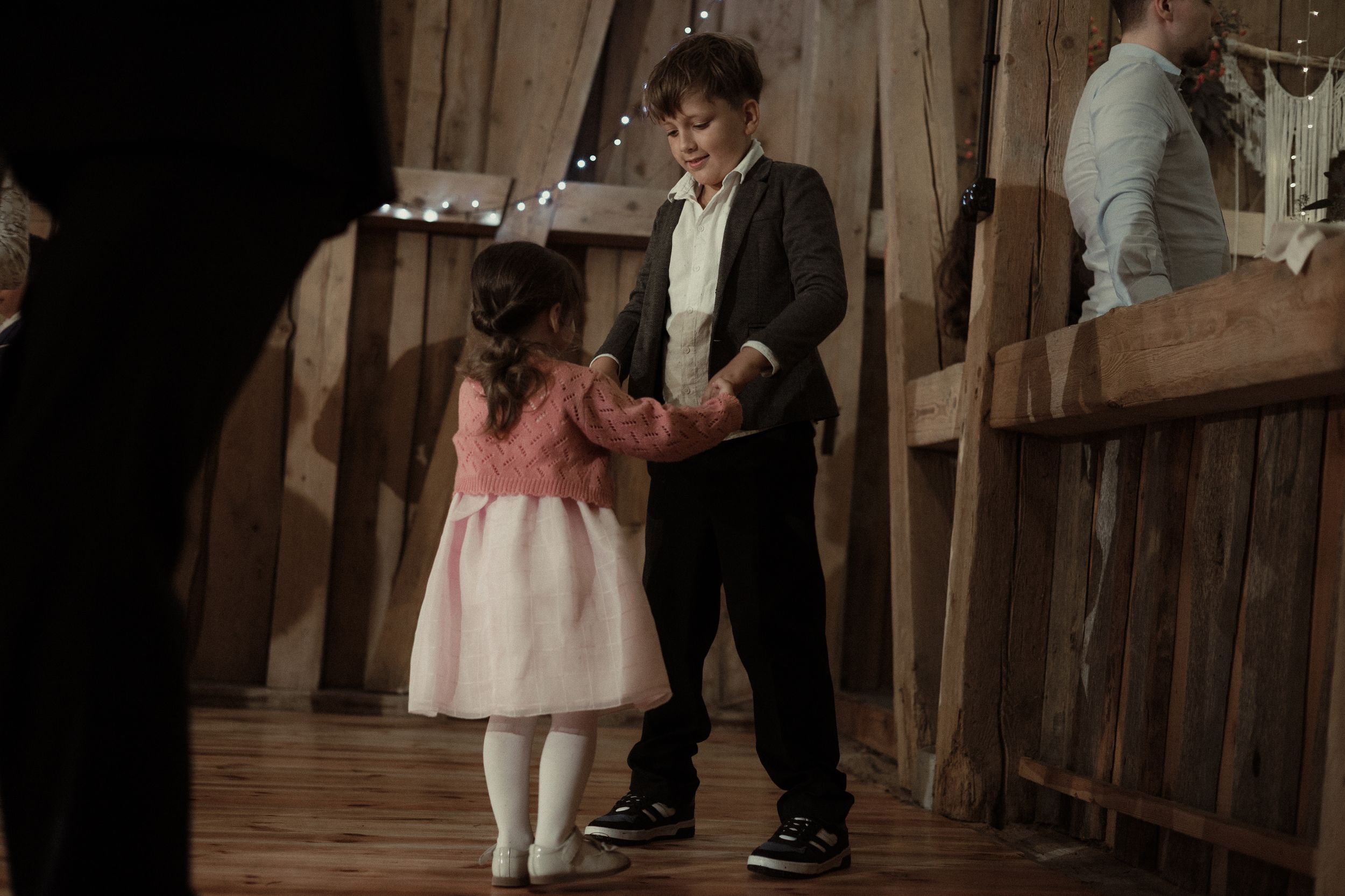 People dancing at what appears to be a rustic wedding venue with wooden walls and floors.
