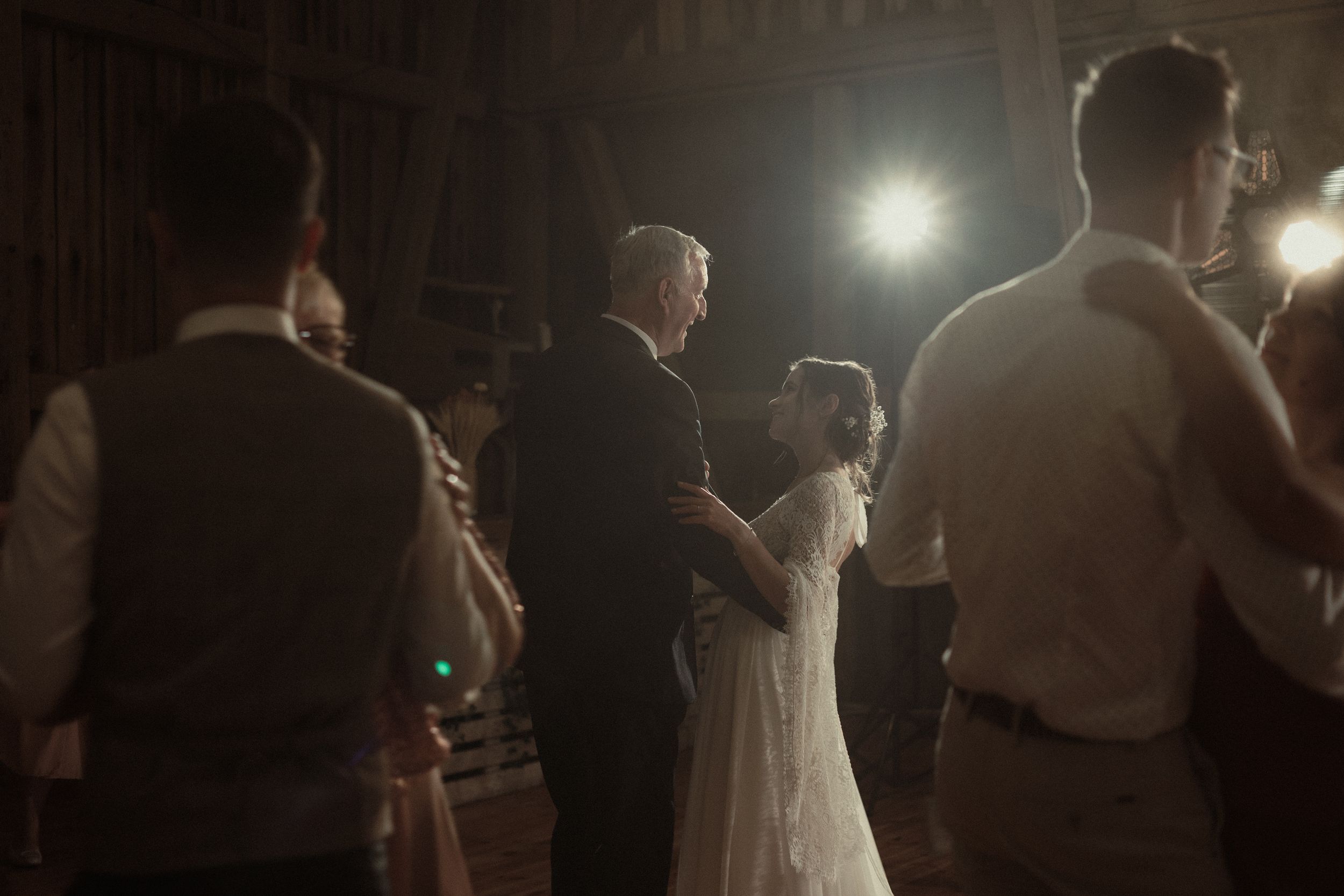 Couple having their first dance in a dimly lit wedding reception venue with spotlights illuminating the scene.