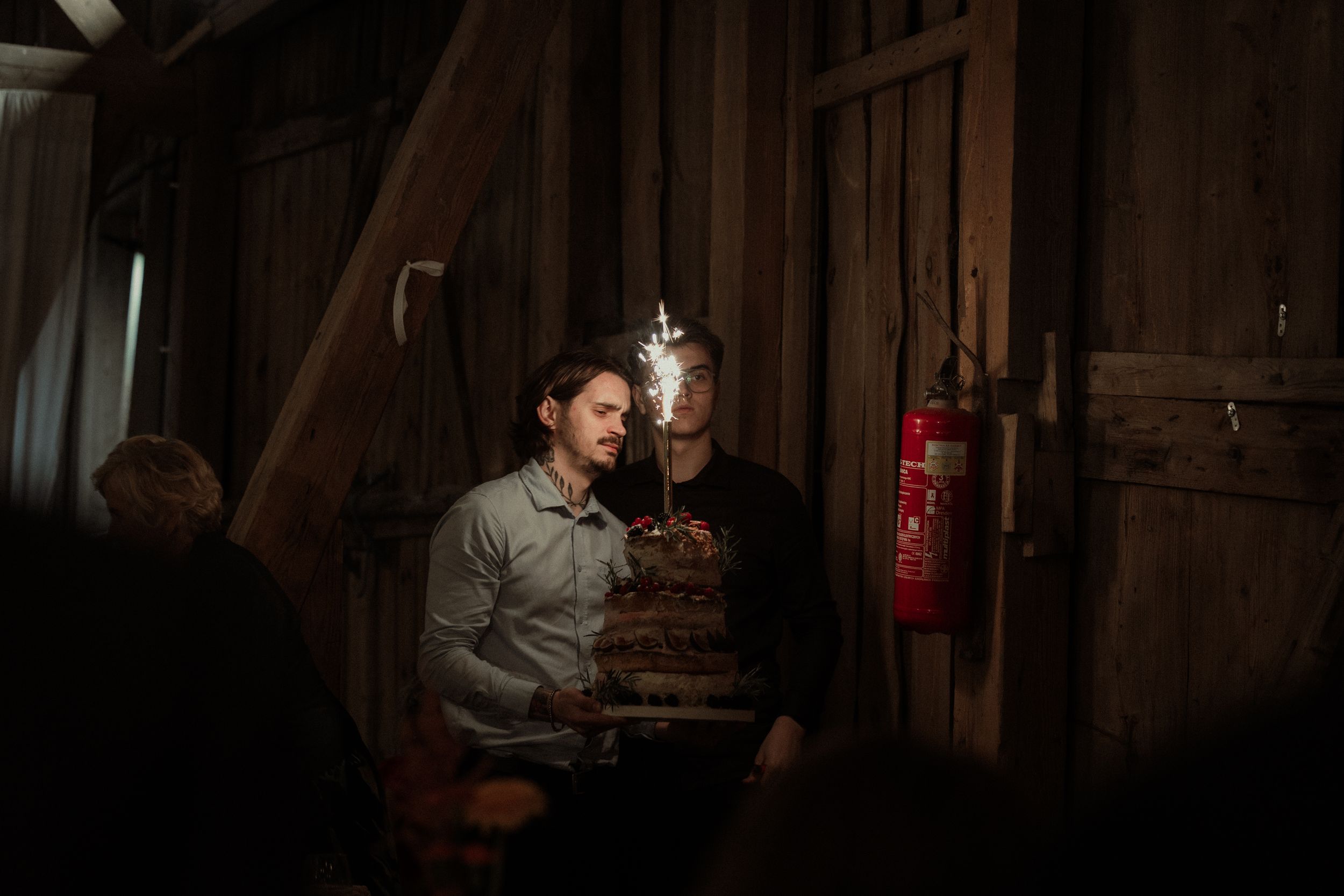 A dark, moody bar interior at night with patrons seated at tables under warm lighting.