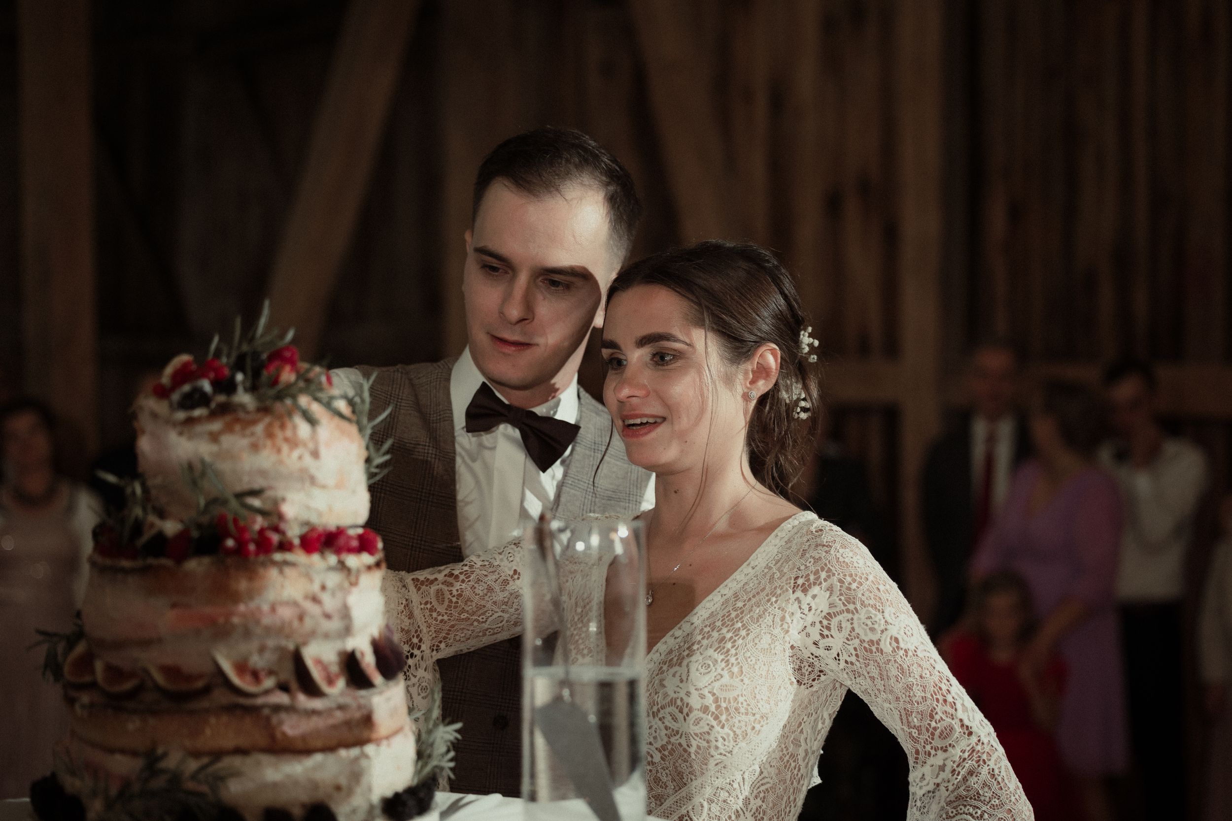 Two people celebrating their wedding in a rustic barn venue with romantic lighting and wooden interior details.