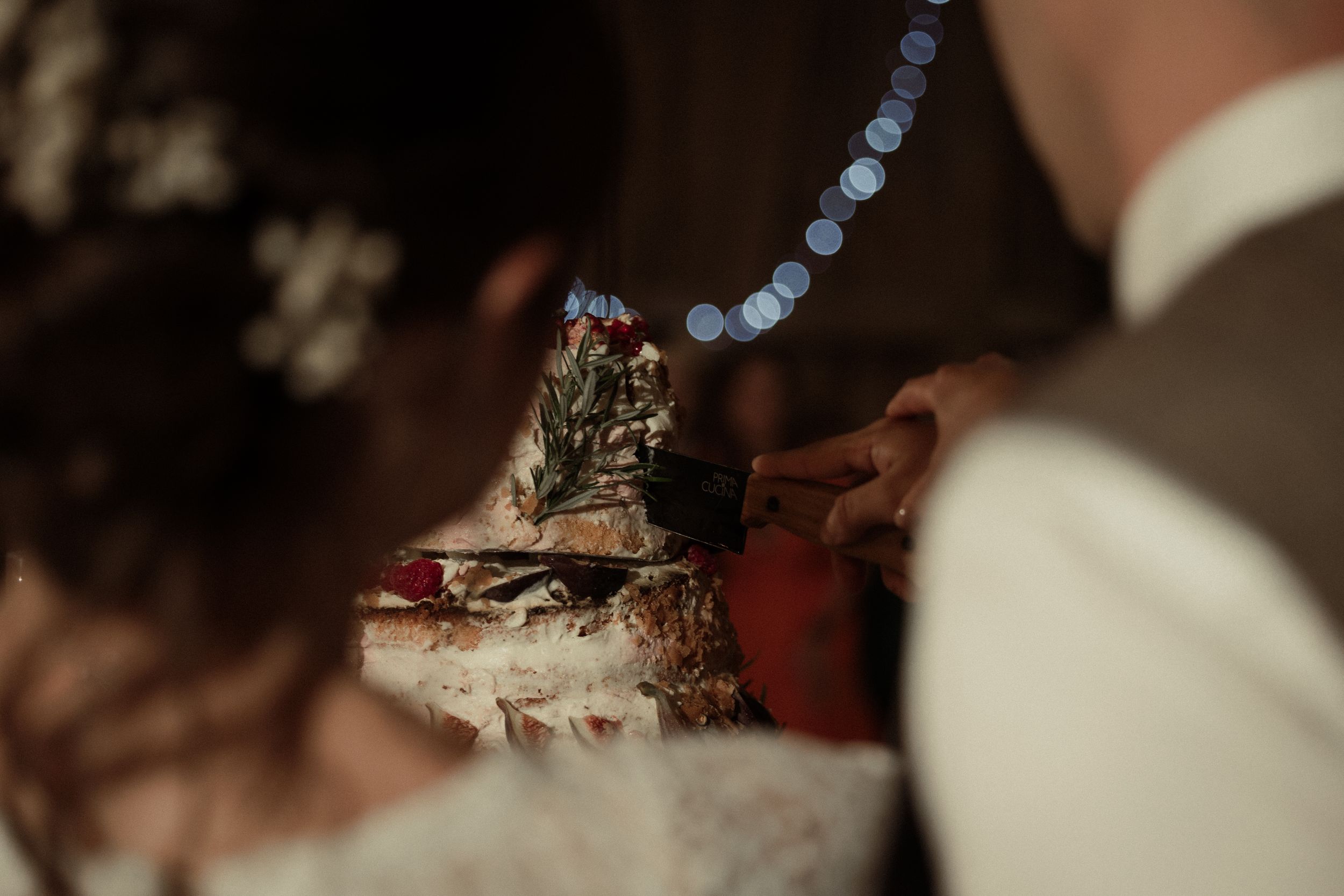 A romantic candlelit wedding reception features wine glasses and decorative floral arrangements at dusk.